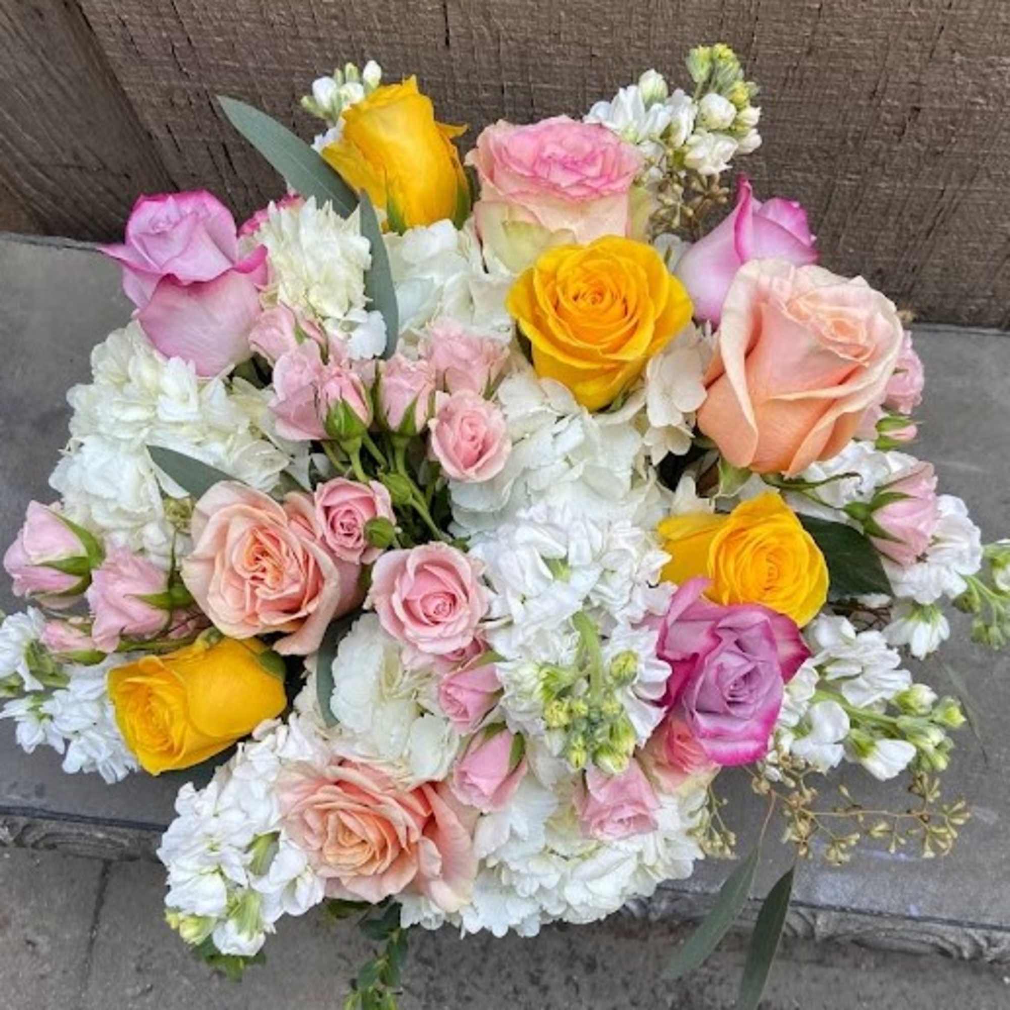Bouquet of pink, peach, and yellow roses with white flowers