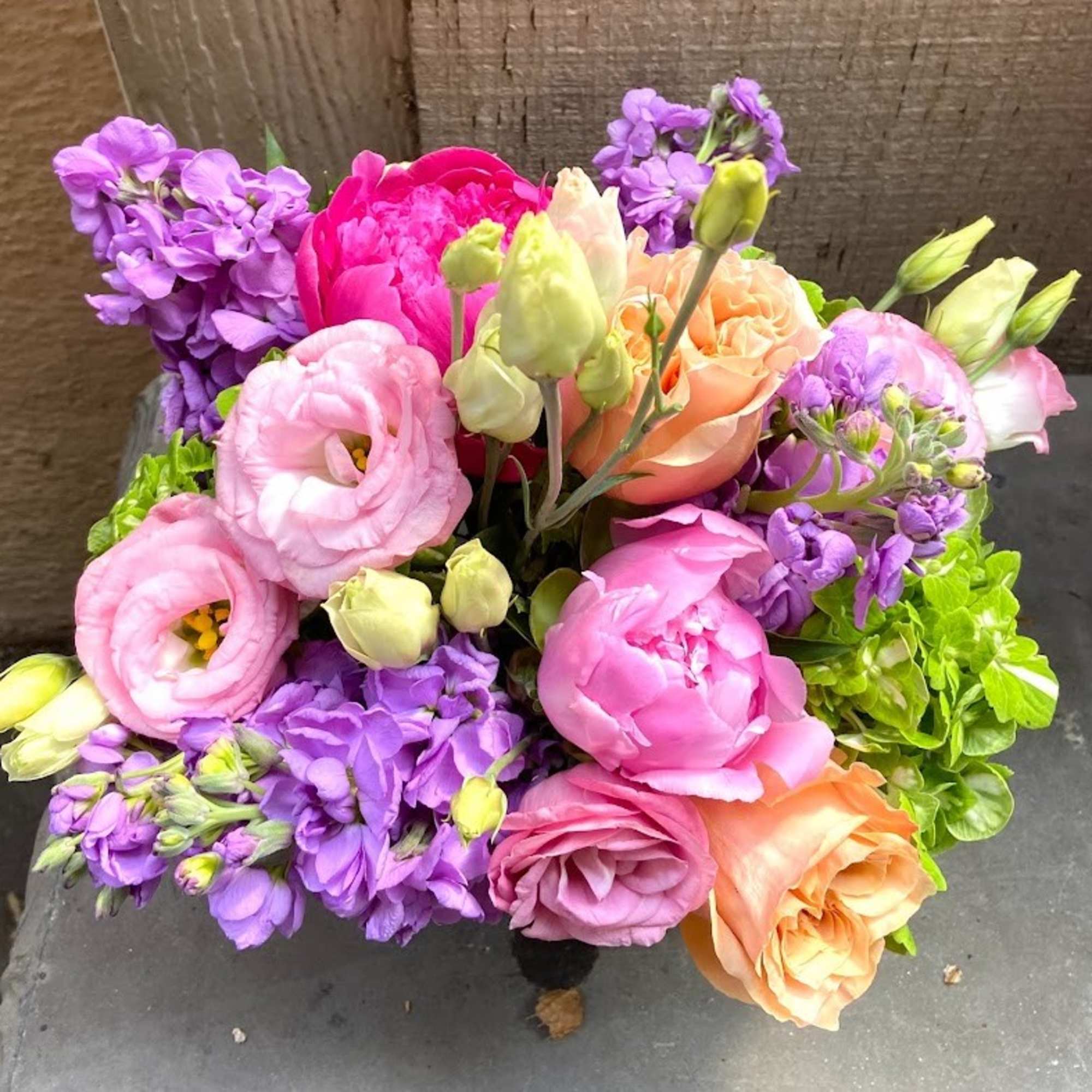 Bouquet of pink, purple, and peach flowers with green accents