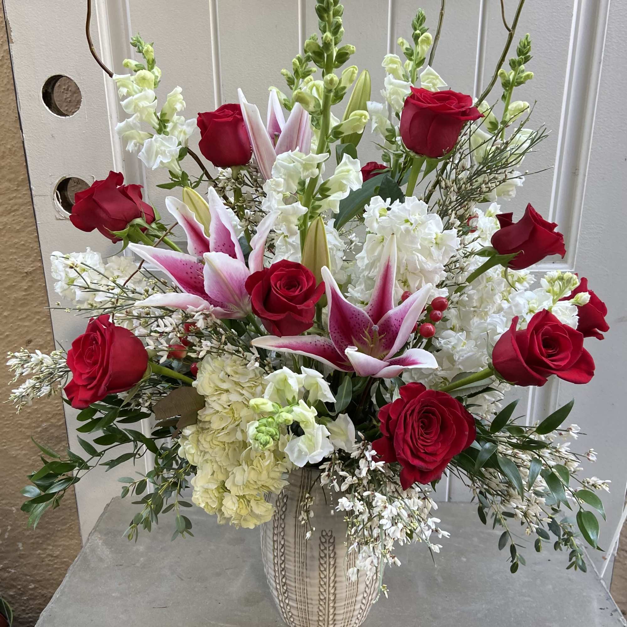 Bouquet of red roses and pink lilies in a ceramic vase