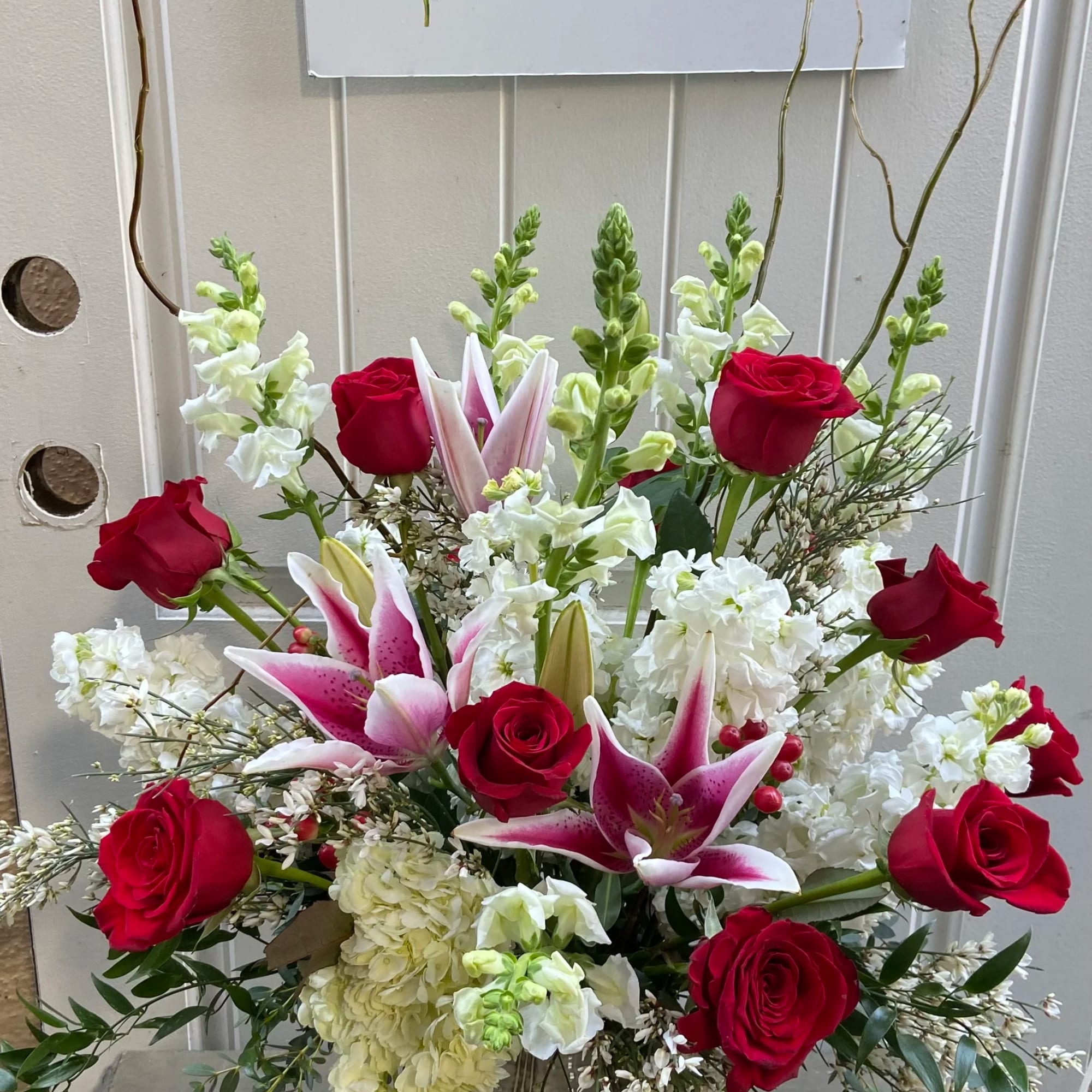 Red roses and pink lilies in a tall vase arrangement