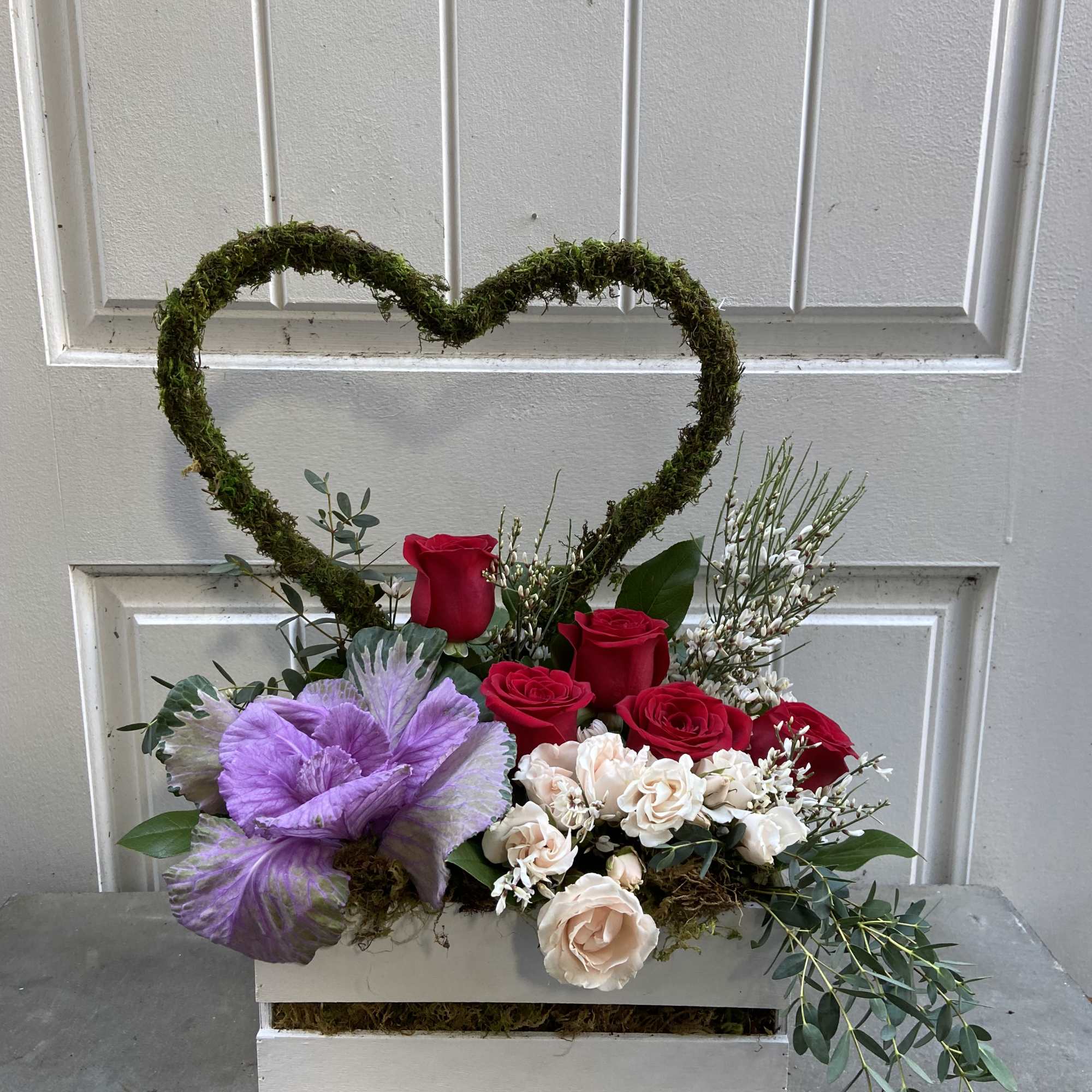 Heart-shaped moss arrangement with roses and pastel flowers in a white box