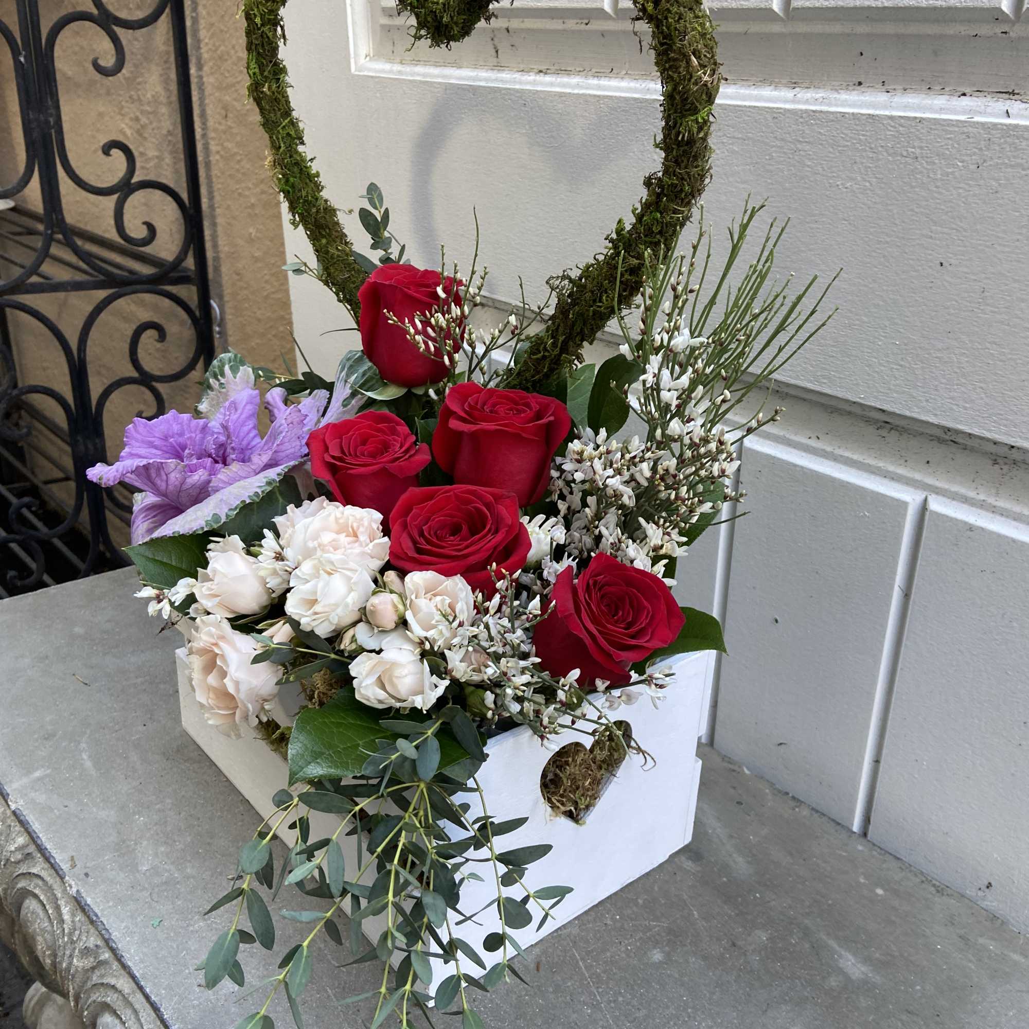 Heart-shaped floral arrangement with red and white roses in a white box