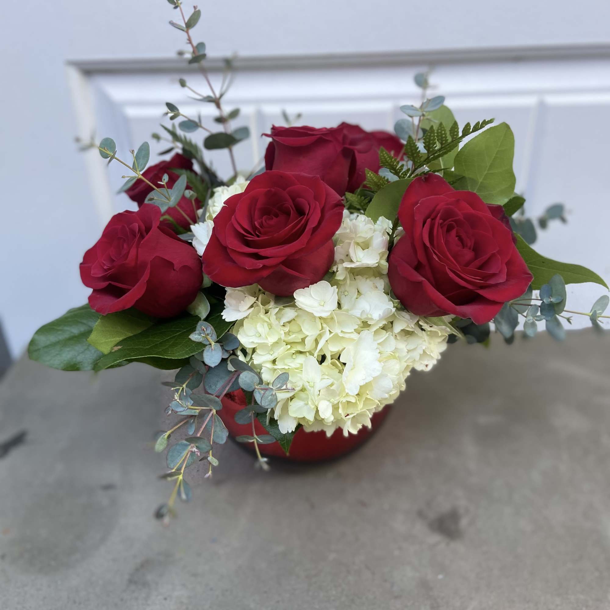 Red roses with white hydrangea in a red vase