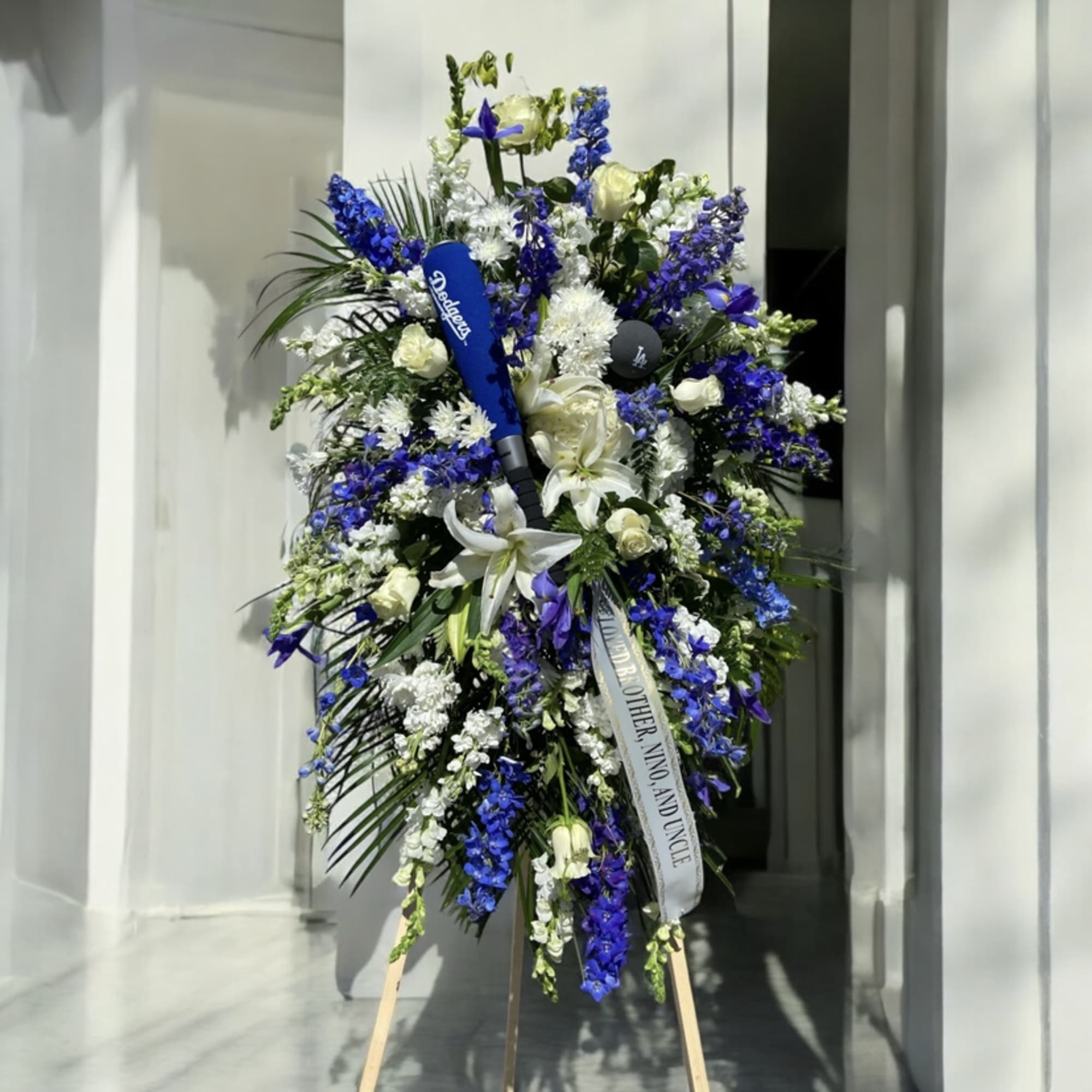 Tall blue and white funeral spray on an easel with ribbon
