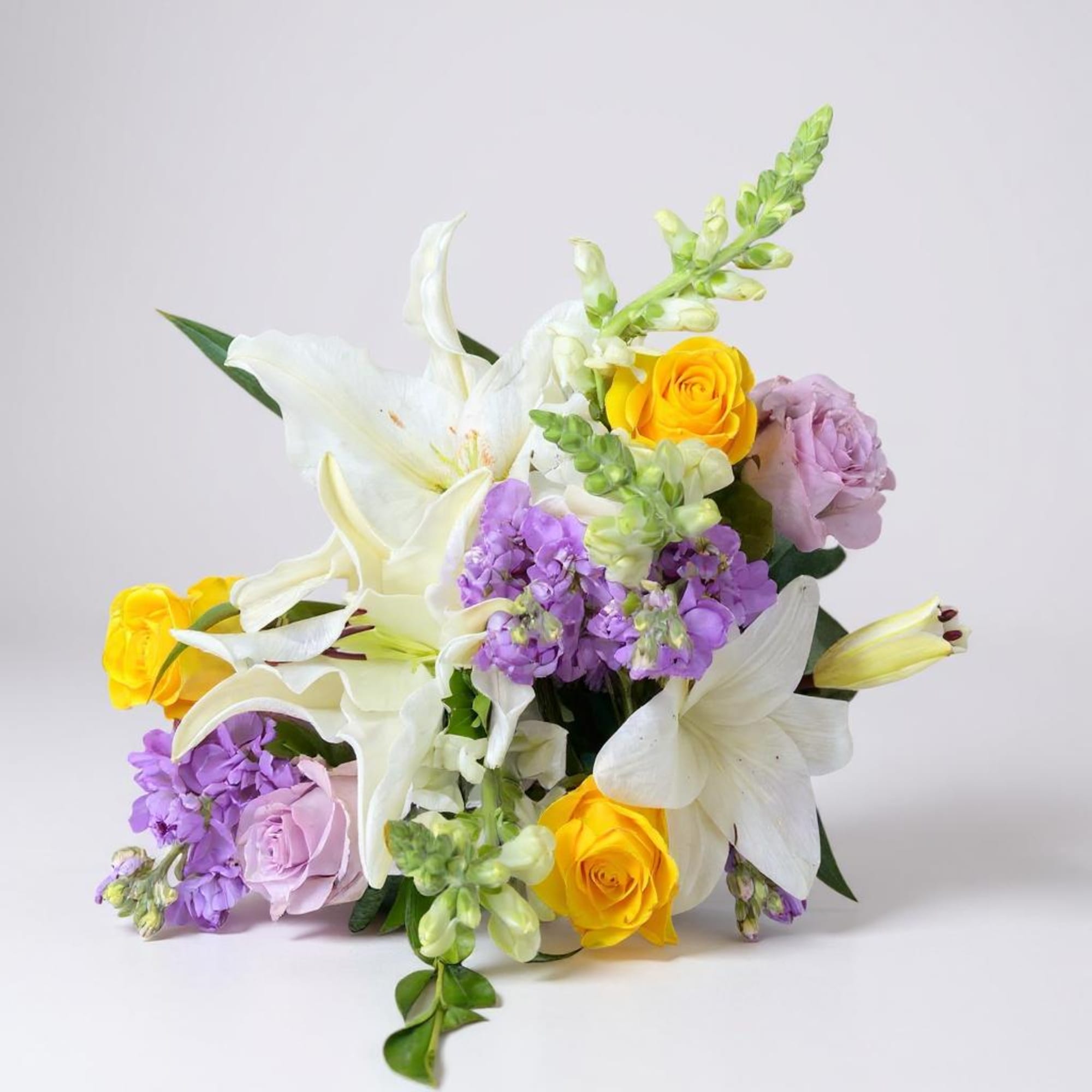 Bouquet of white lilies, yellow roses, and lavender flowers