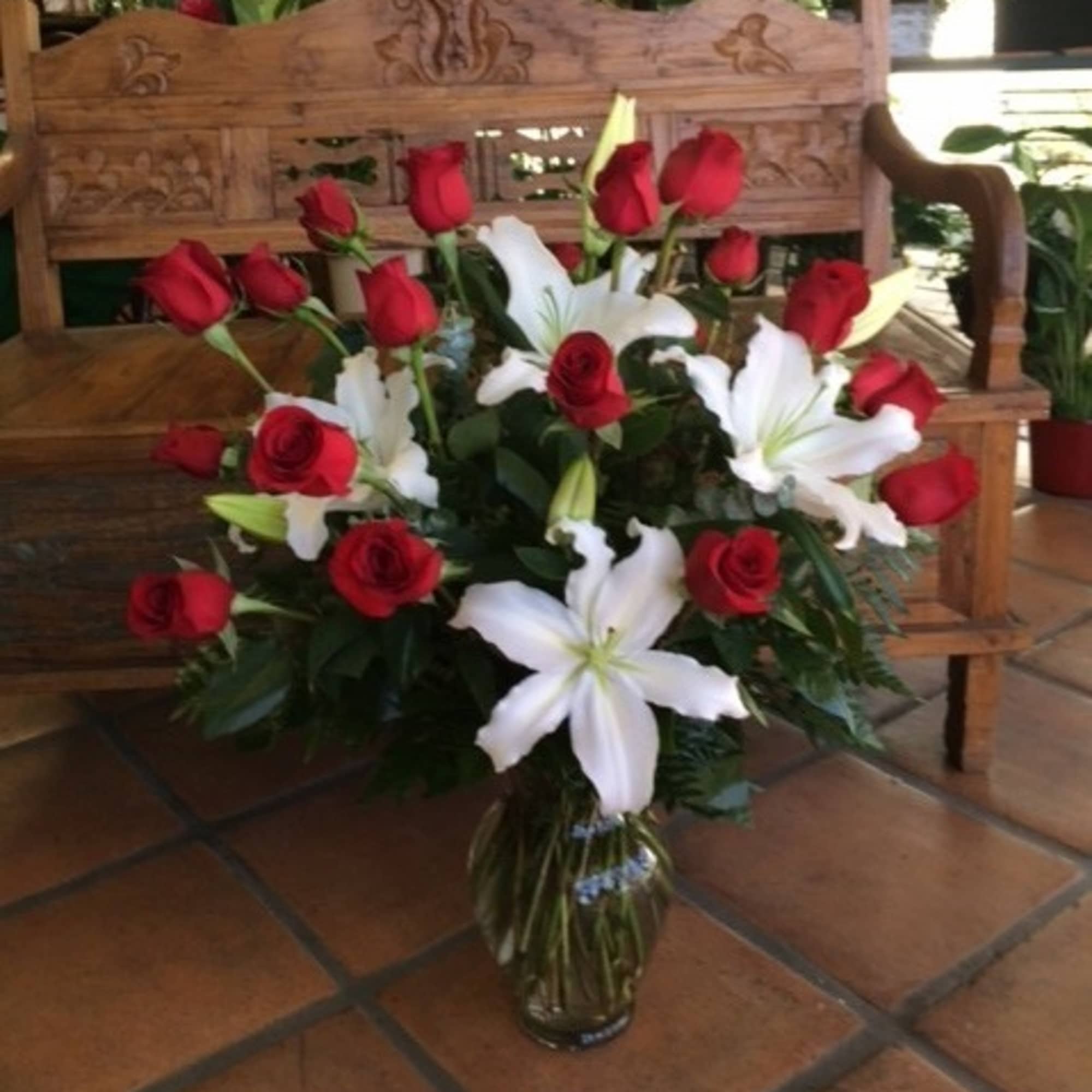 Red roses and white lilies arranged in a glass vase