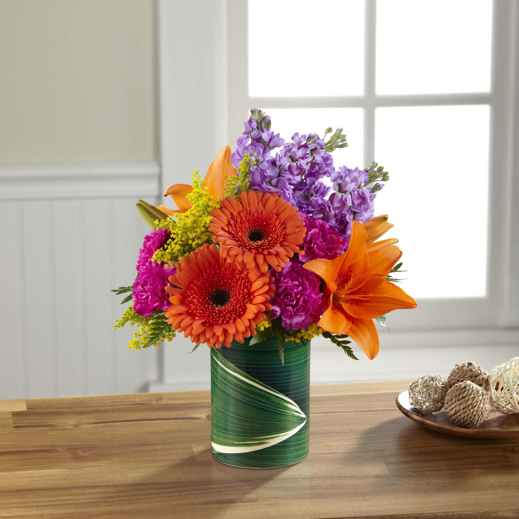 Orange lilies and gerbera daisies in a green vase