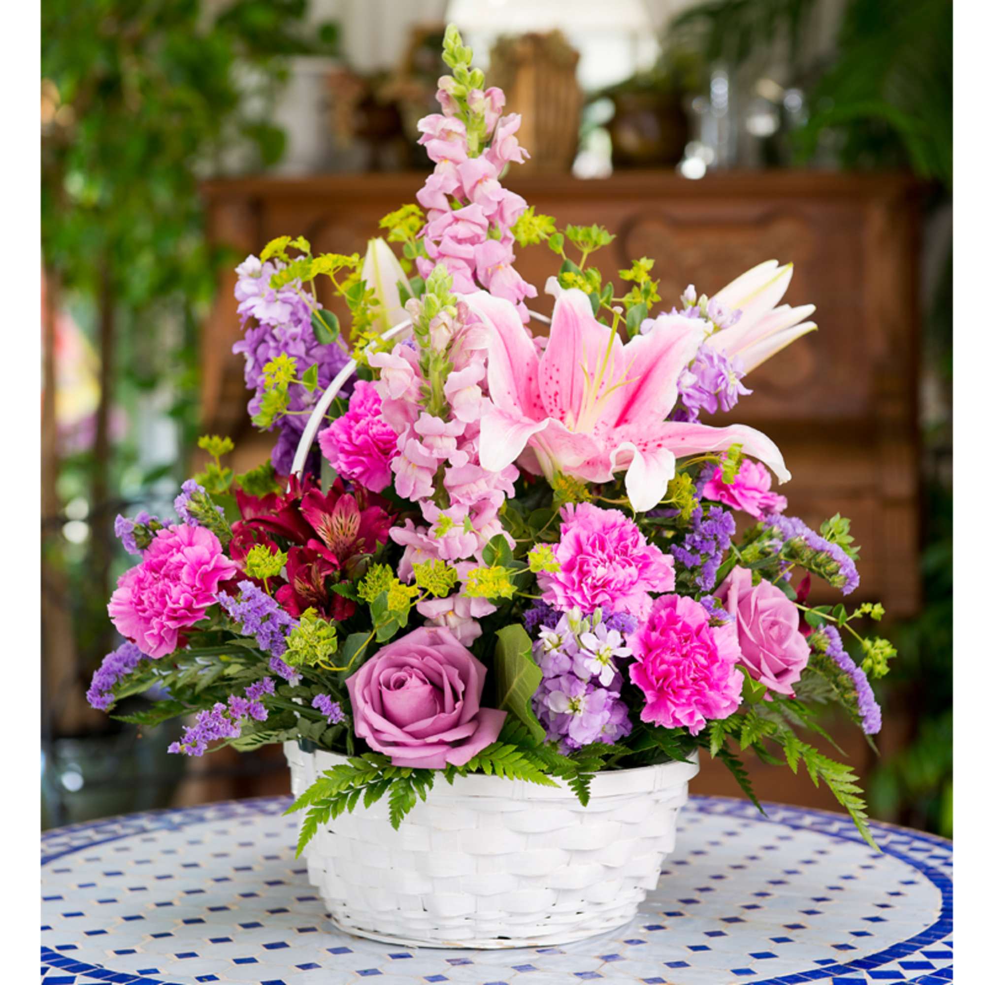 Pink and purple flower arrangement in a white basket