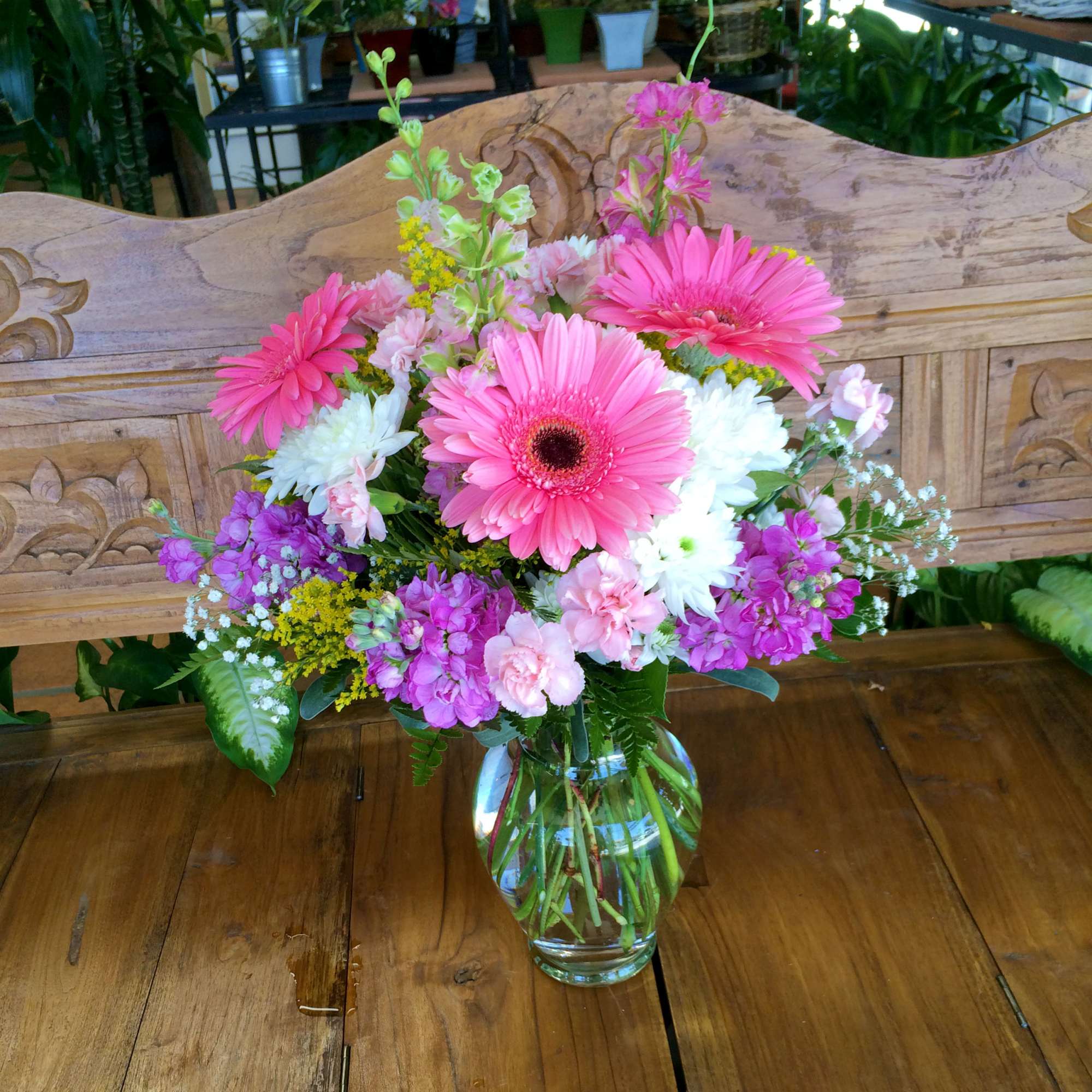 Pink gerbera daisies and mixed blooms in a glass vase