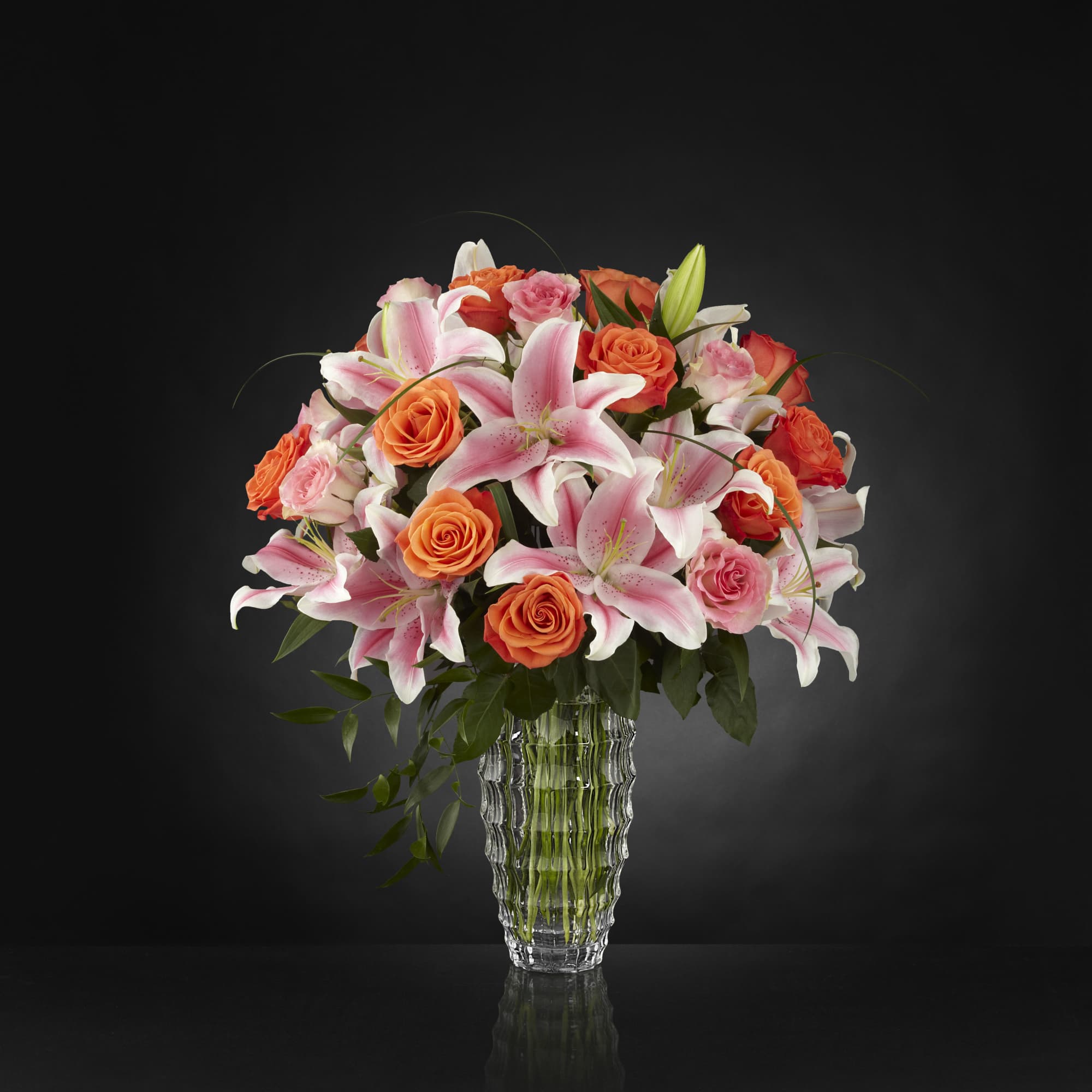 Pink lilies and orange roses in a clear glass vase