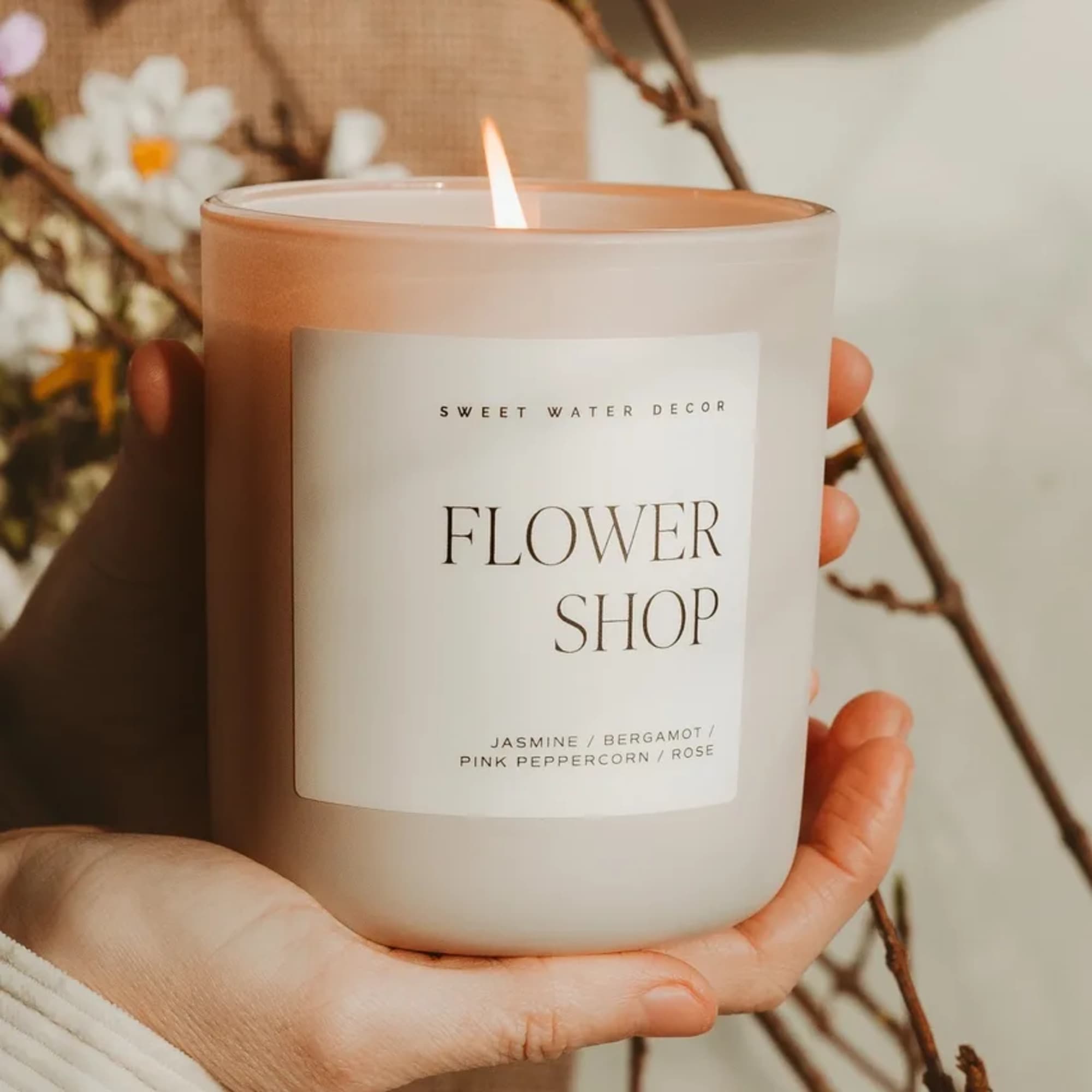 Lit flower shop candle in a frosted glass jar