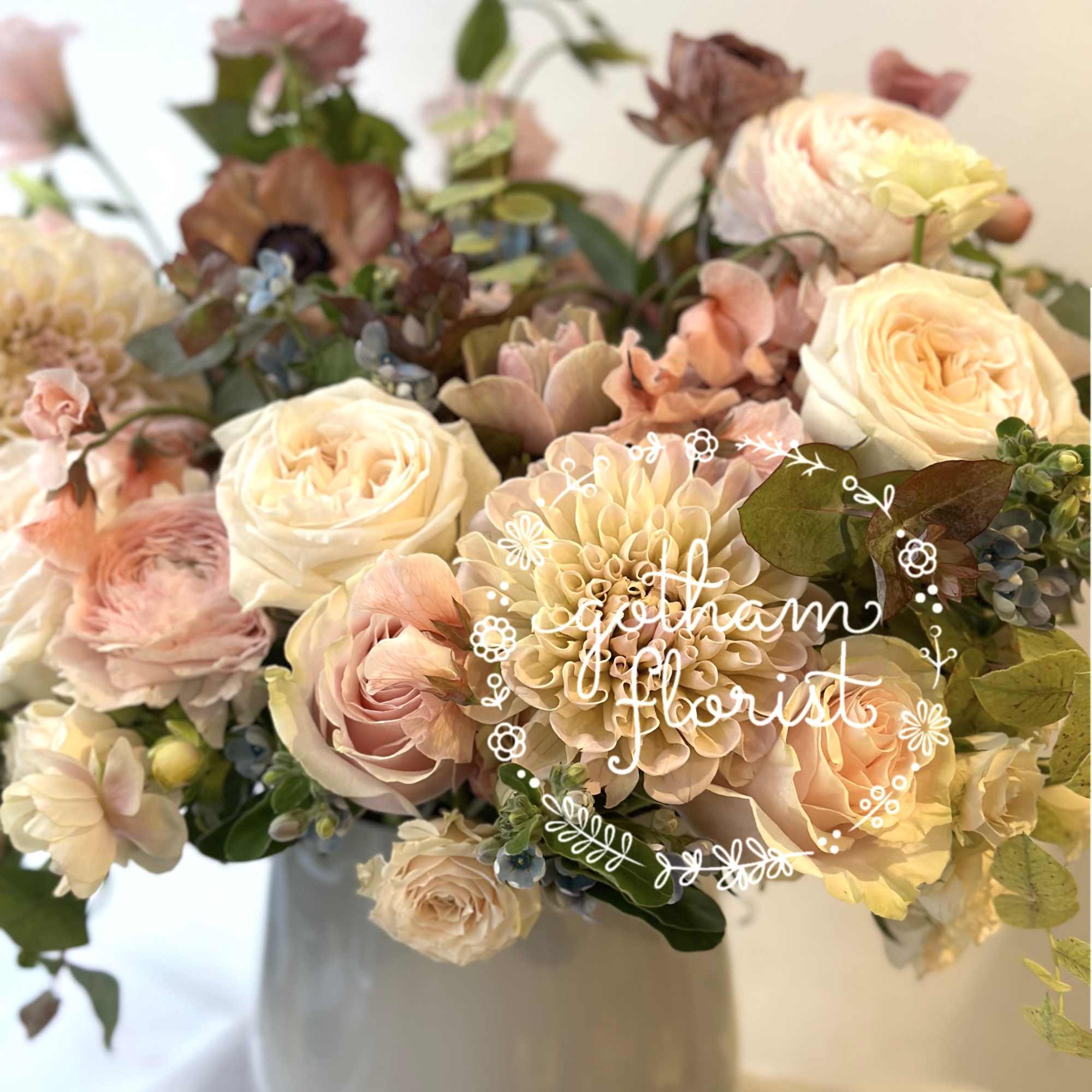 Pastel bouquet of roses and dahlias in a white vase