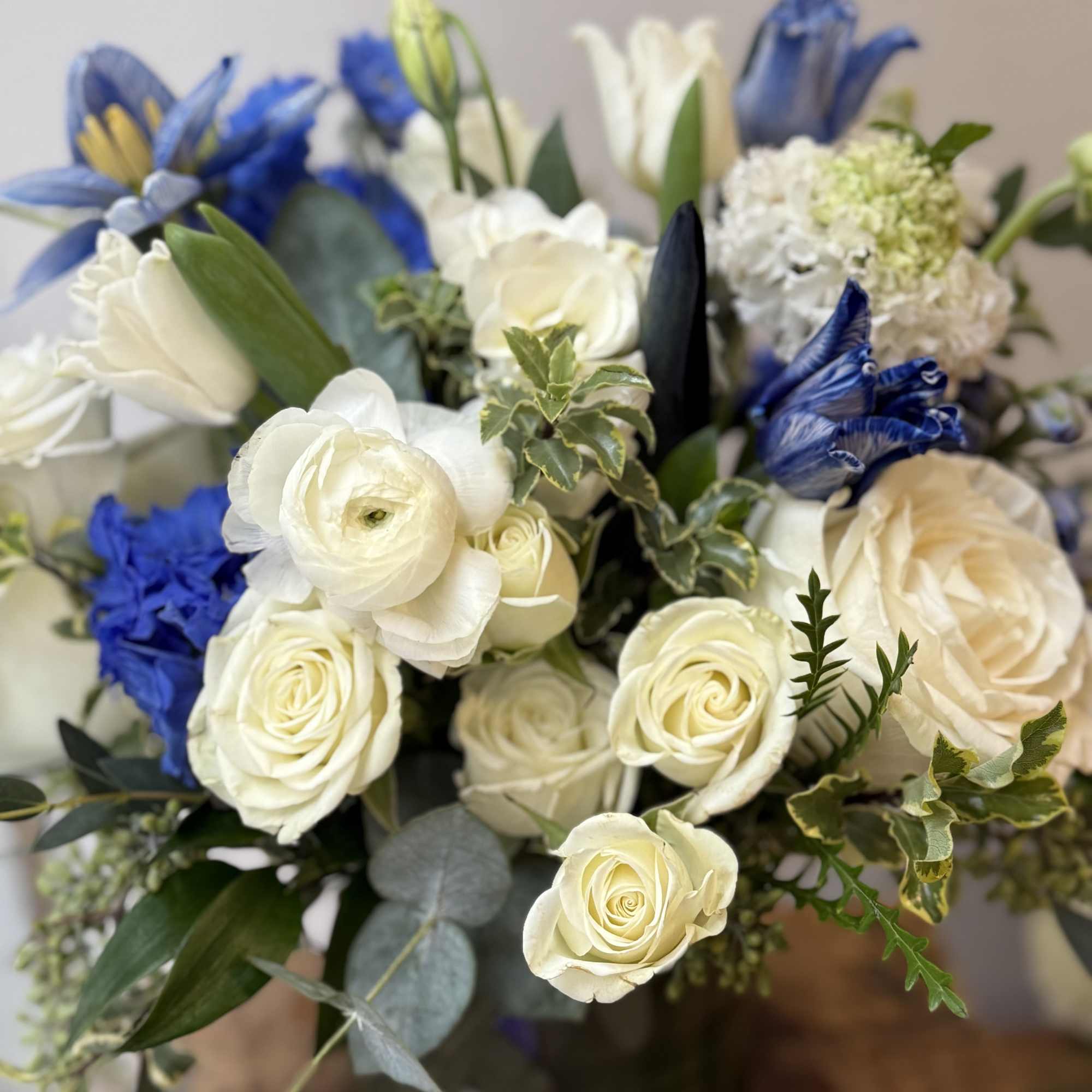 Bouquet of white roses and blue flowers with greenery