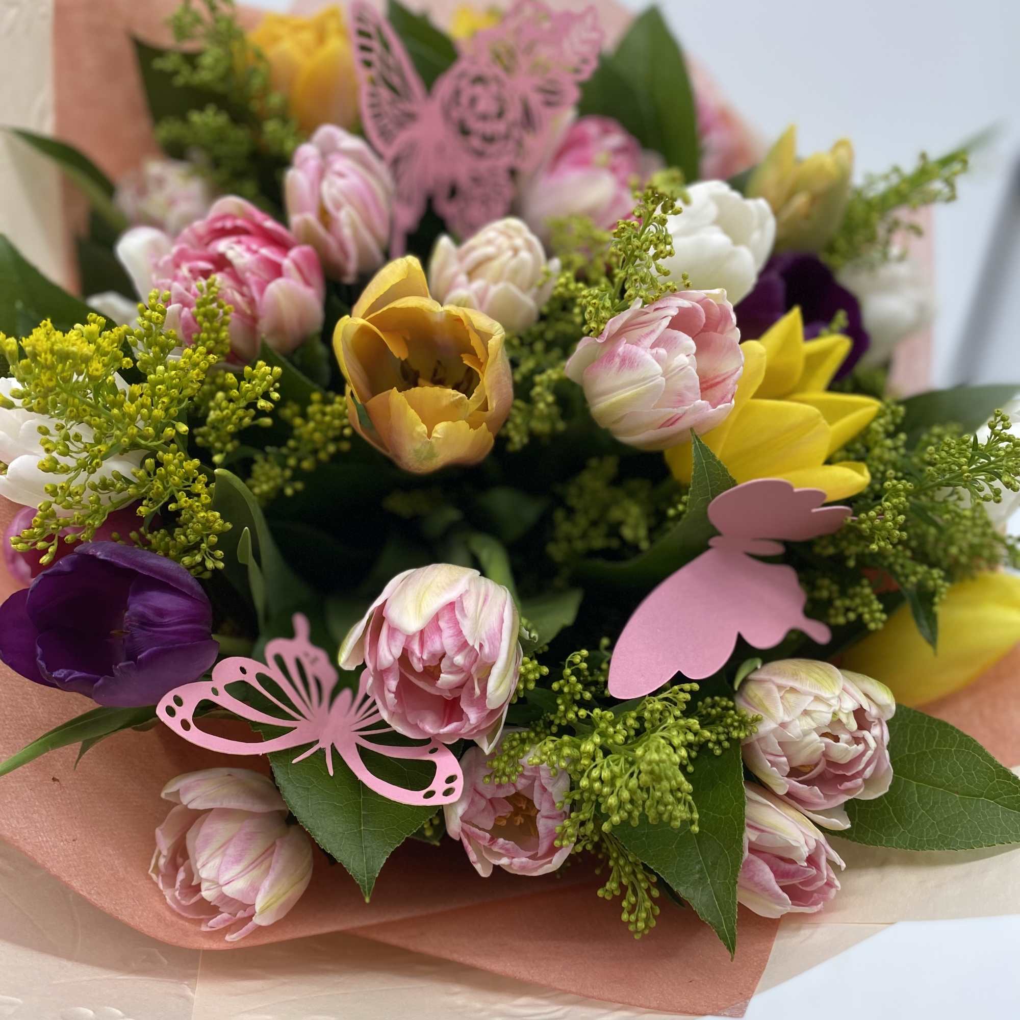 Bouquet of pink, yellow, and purple tulips with butterfly picks