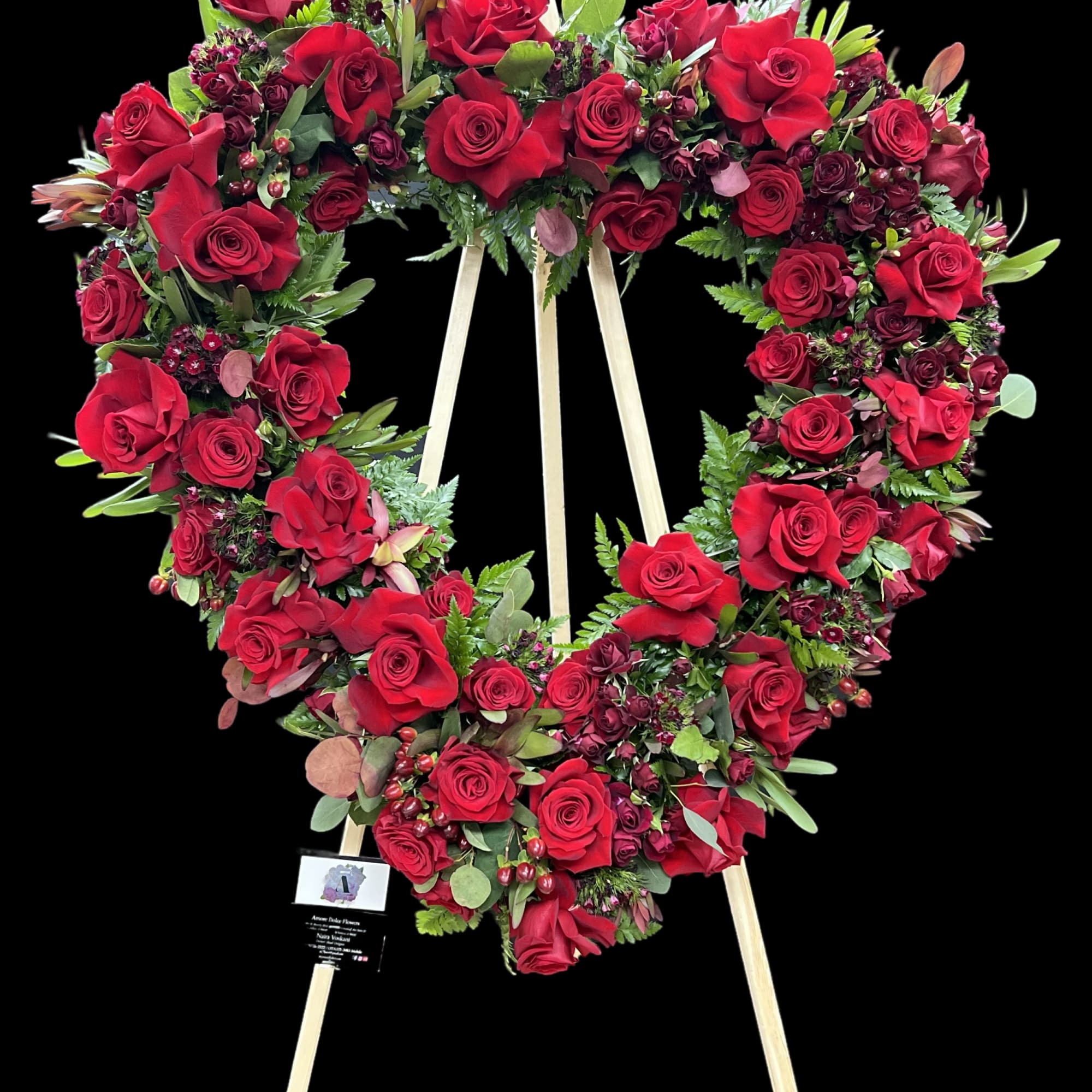 Heart-shaped wreath of red roses on a wooden easel
