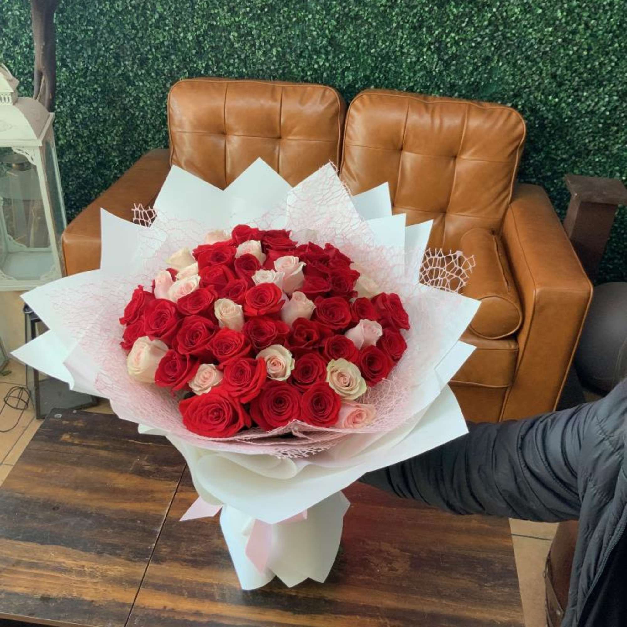 Large bouquet of red and pale pink roses wrapped in white paper