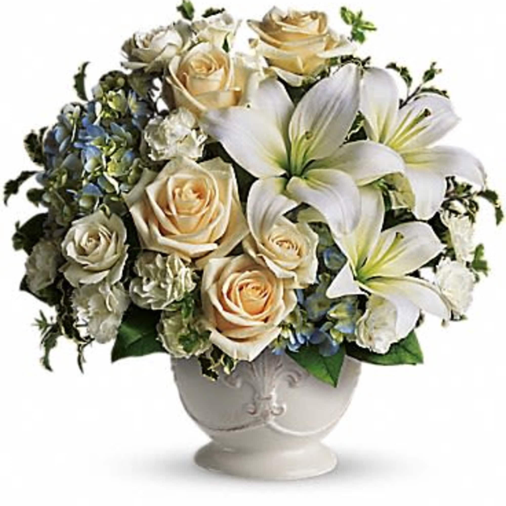 Cream roses and white lilies arranged in a white vase