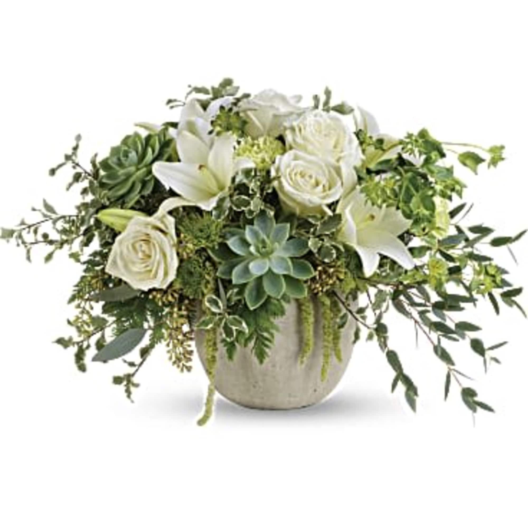 White roses and lilies in a low ceramic vase with trailing greenery