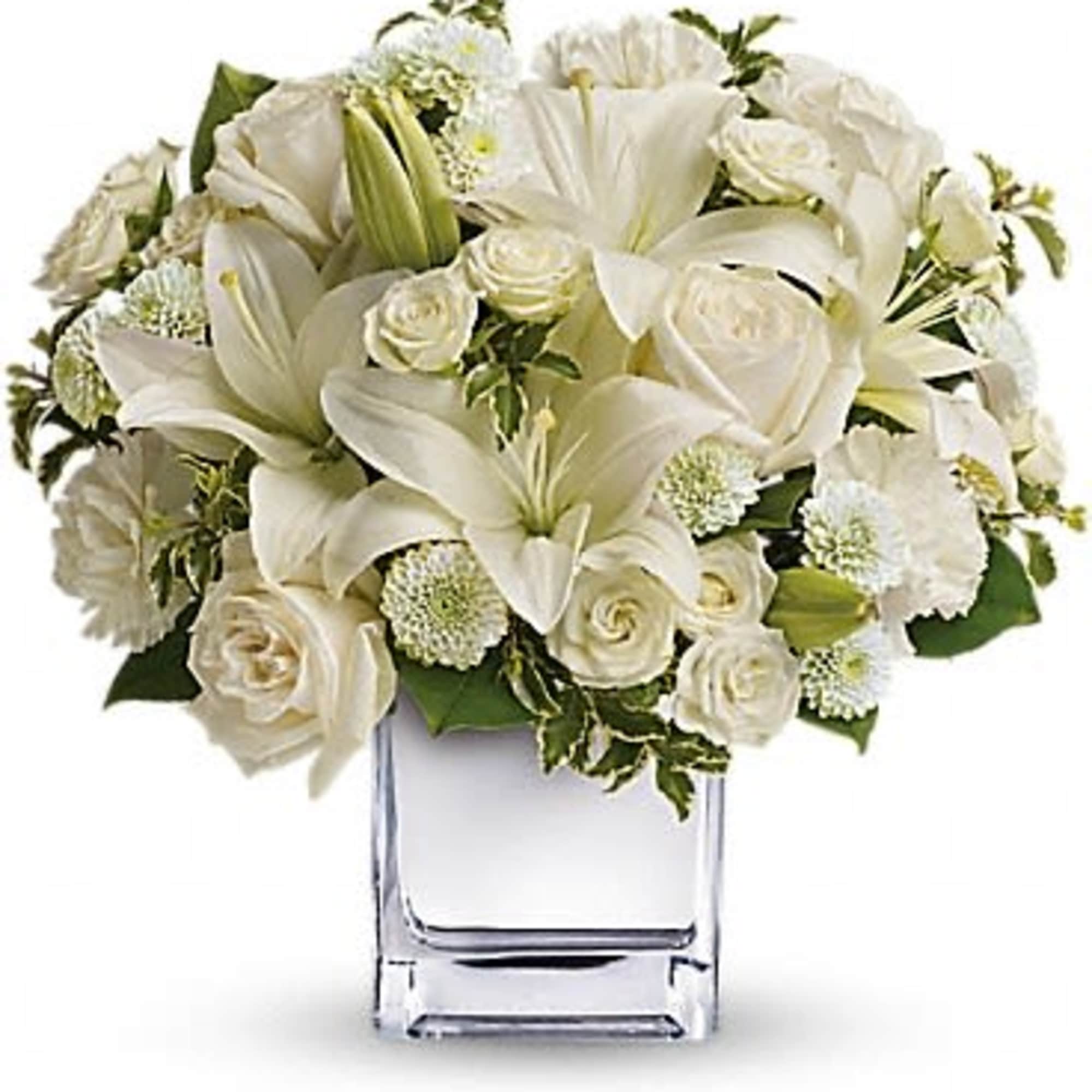 White lilies and roses arranged in a clear glass vase