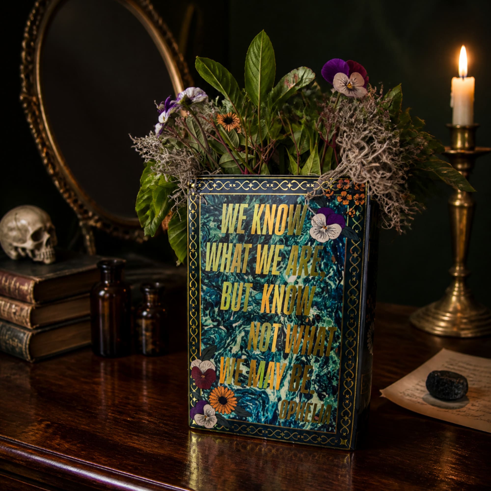 Decorative floral arrangement in a book-shaped container with a lit candle nearby