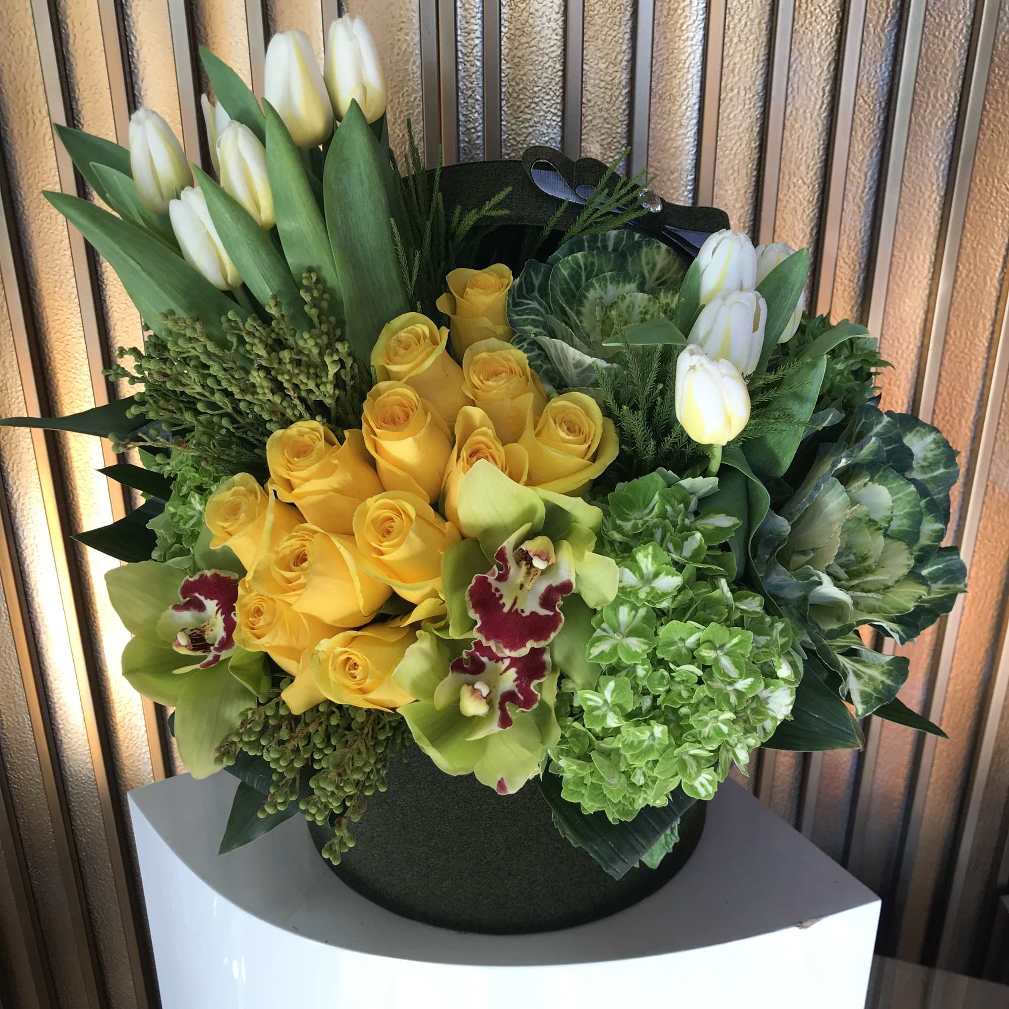 Yellow roses and white tulips arranged in a black hatbox