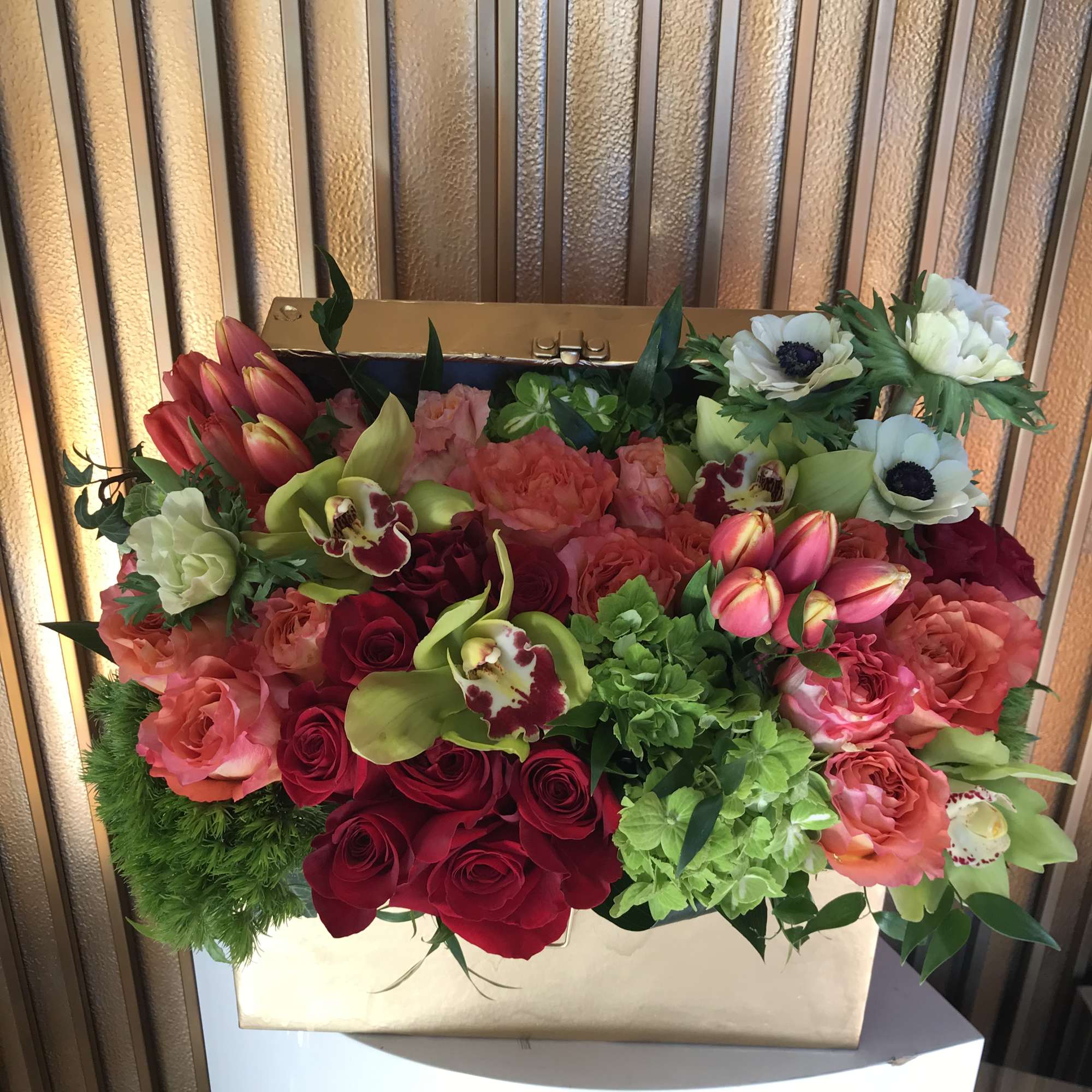 Mixed bouquet of red, pink, and white flowers in a gold box