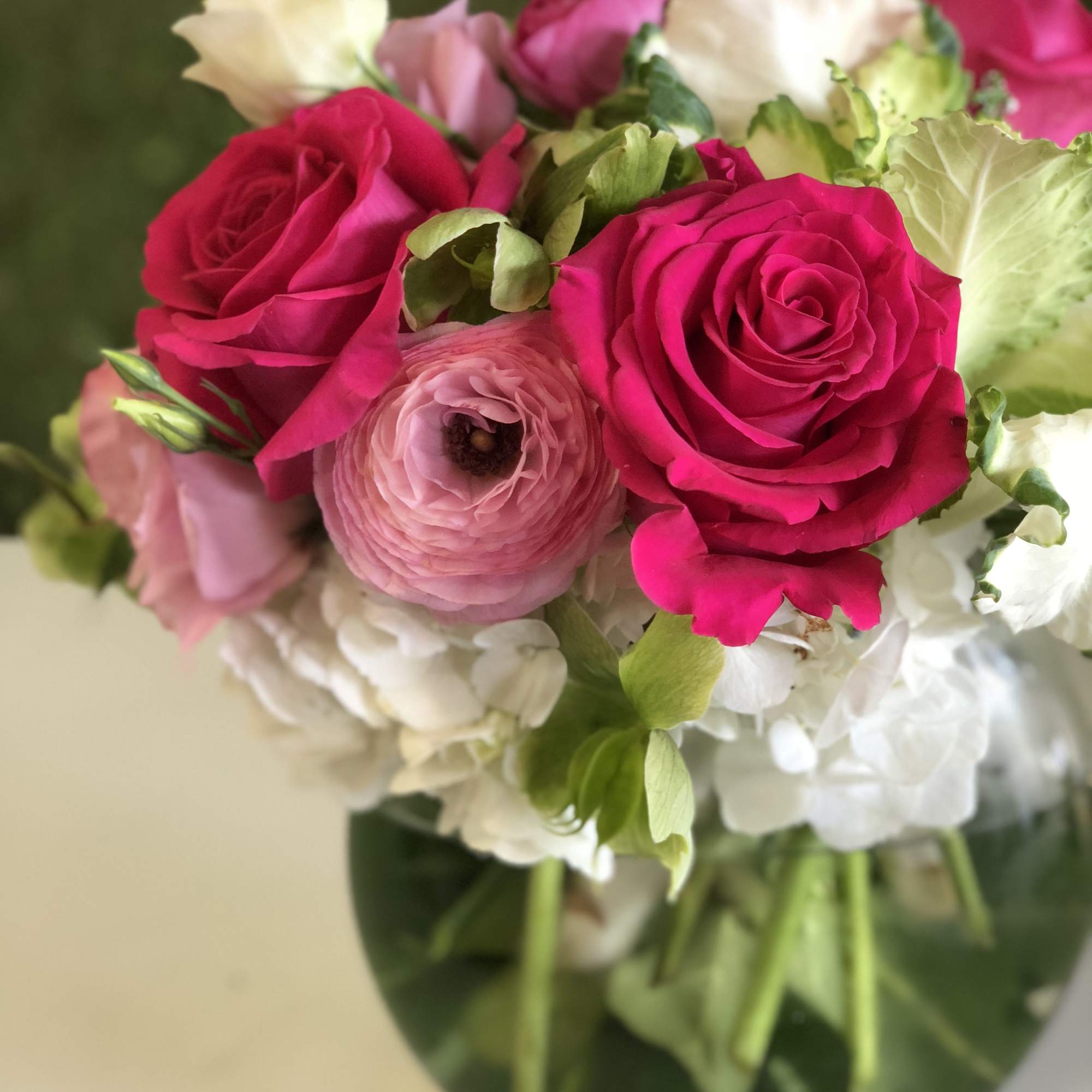 Pink and white bouquet of roses and ranunculus in a glass vase