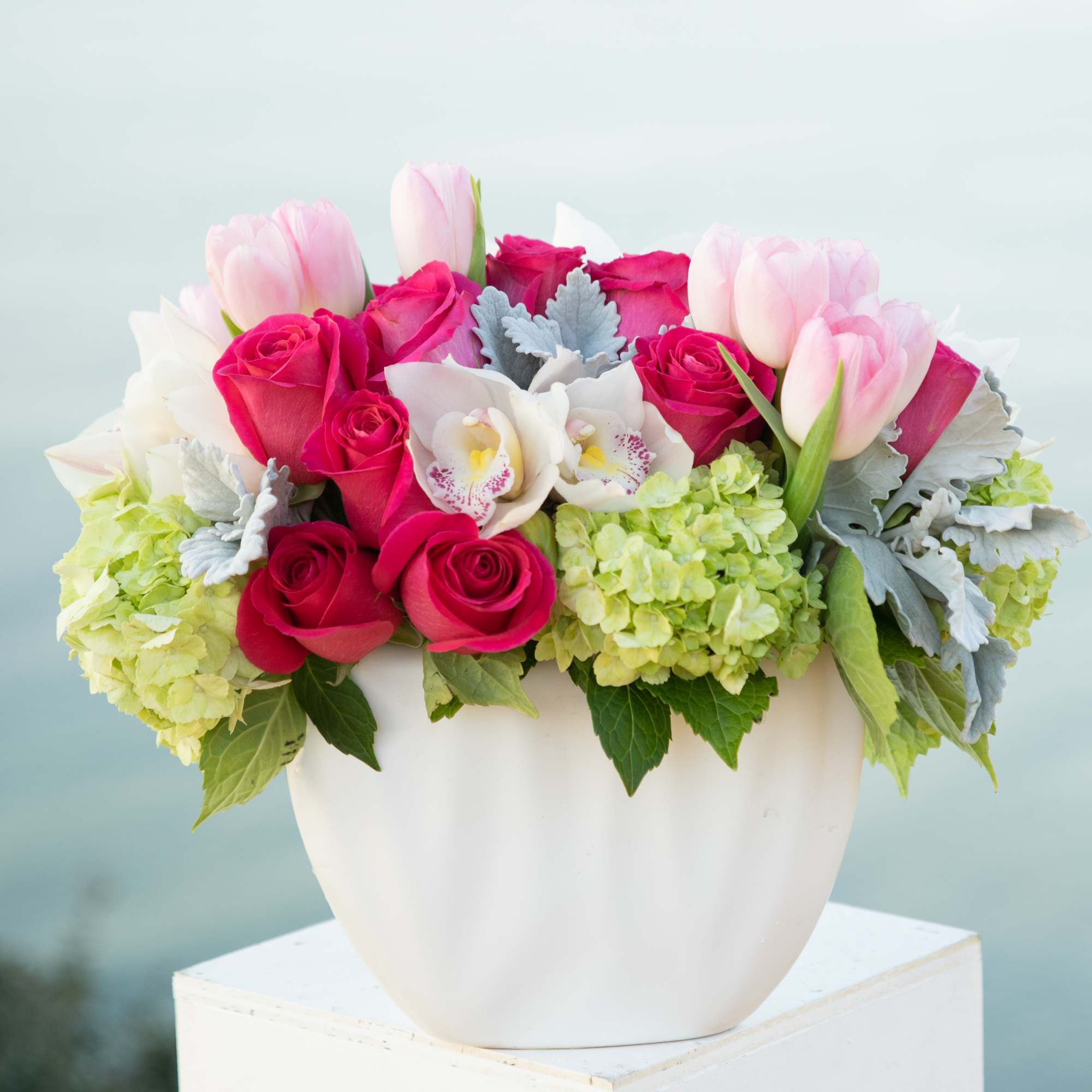 Pink roses and tulips arranged in a white vase