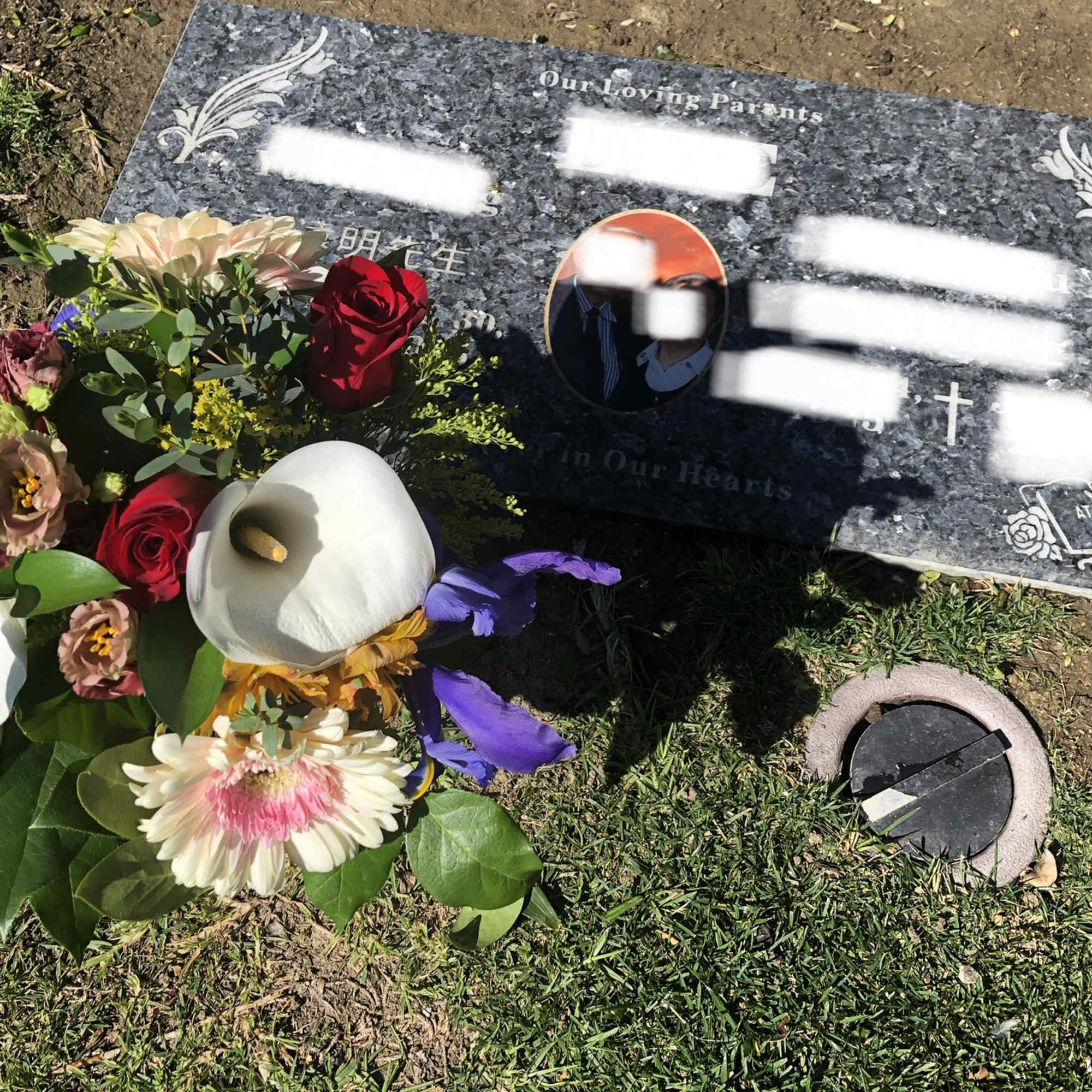 Bouquet of mixed flowers placed beside a gravestone