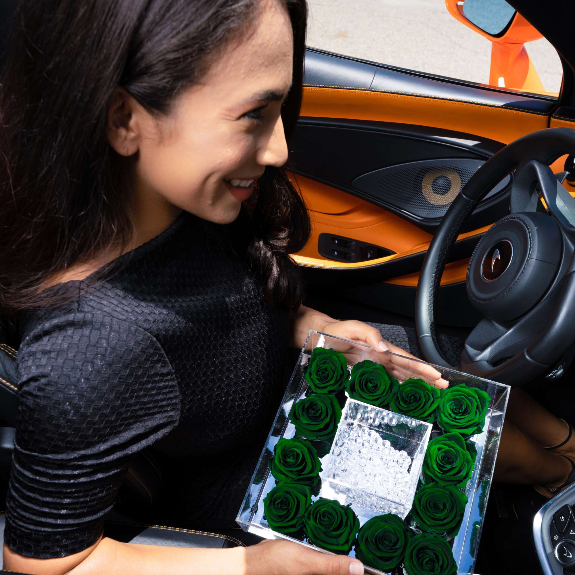 Woman holding a clear box of green roses inside a car