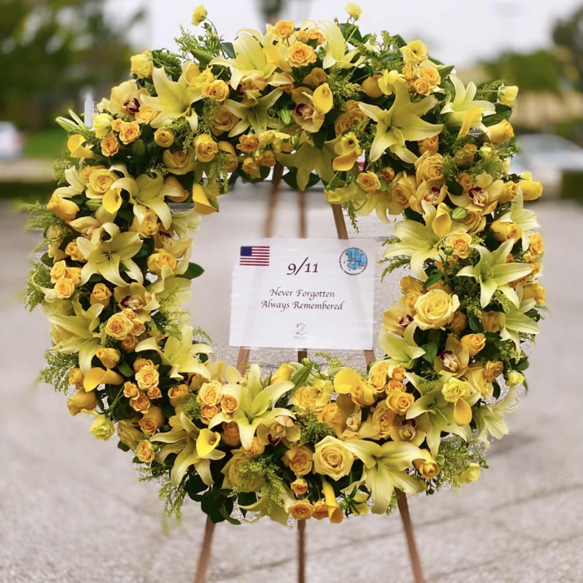Yellow floral wreath on an easel with a 9/11 remembrance sign