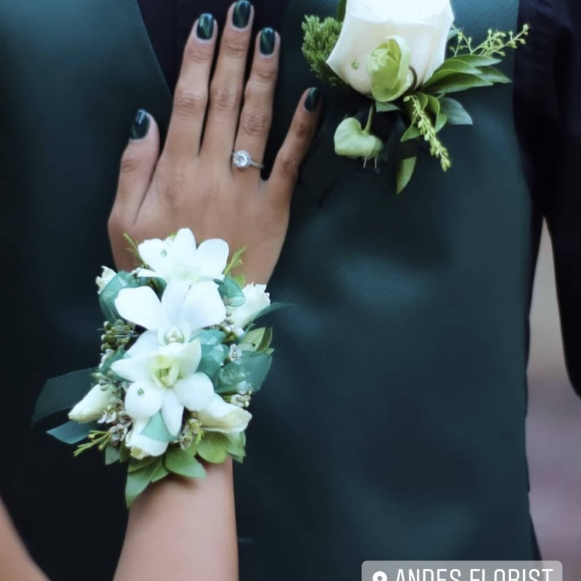White floral wrist corsage and boutonniere on a dark suit