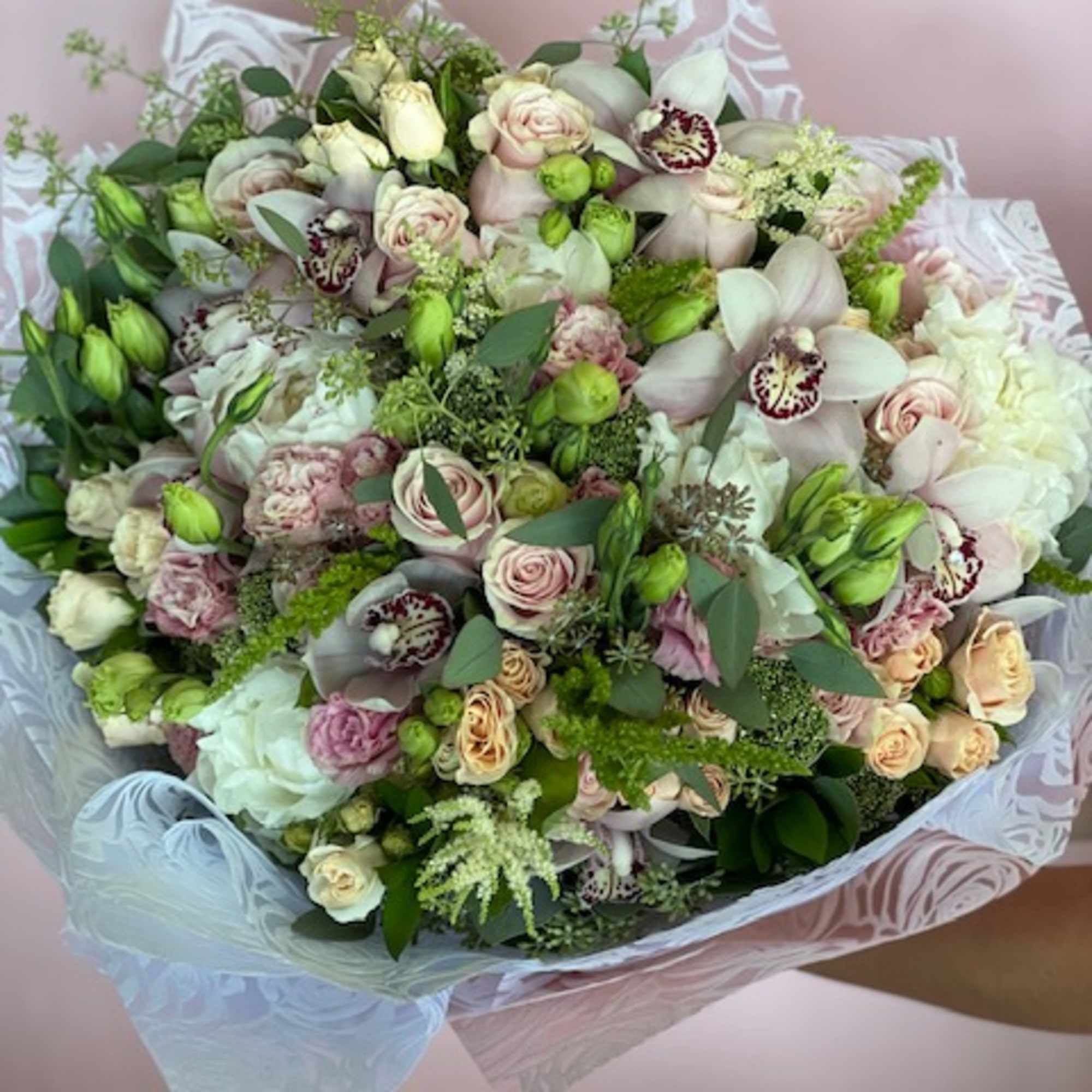 Large bouquet of pale pink and white flowers wrapped in patterned paper