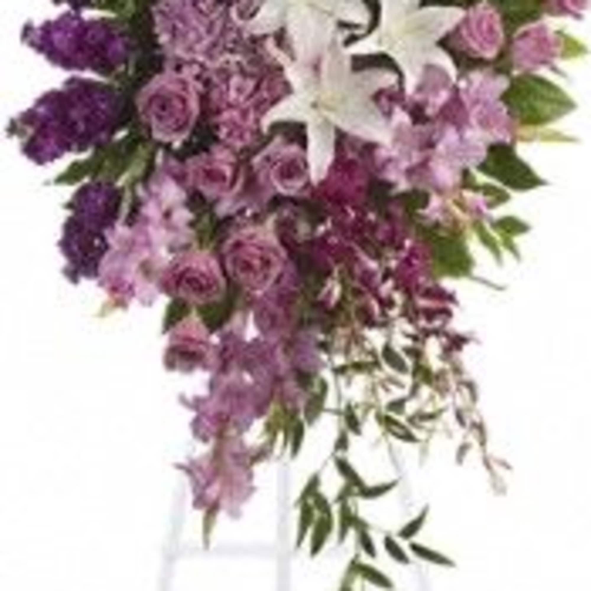 Tall floral spray with purple and pink flowers and white lilies on a stand
