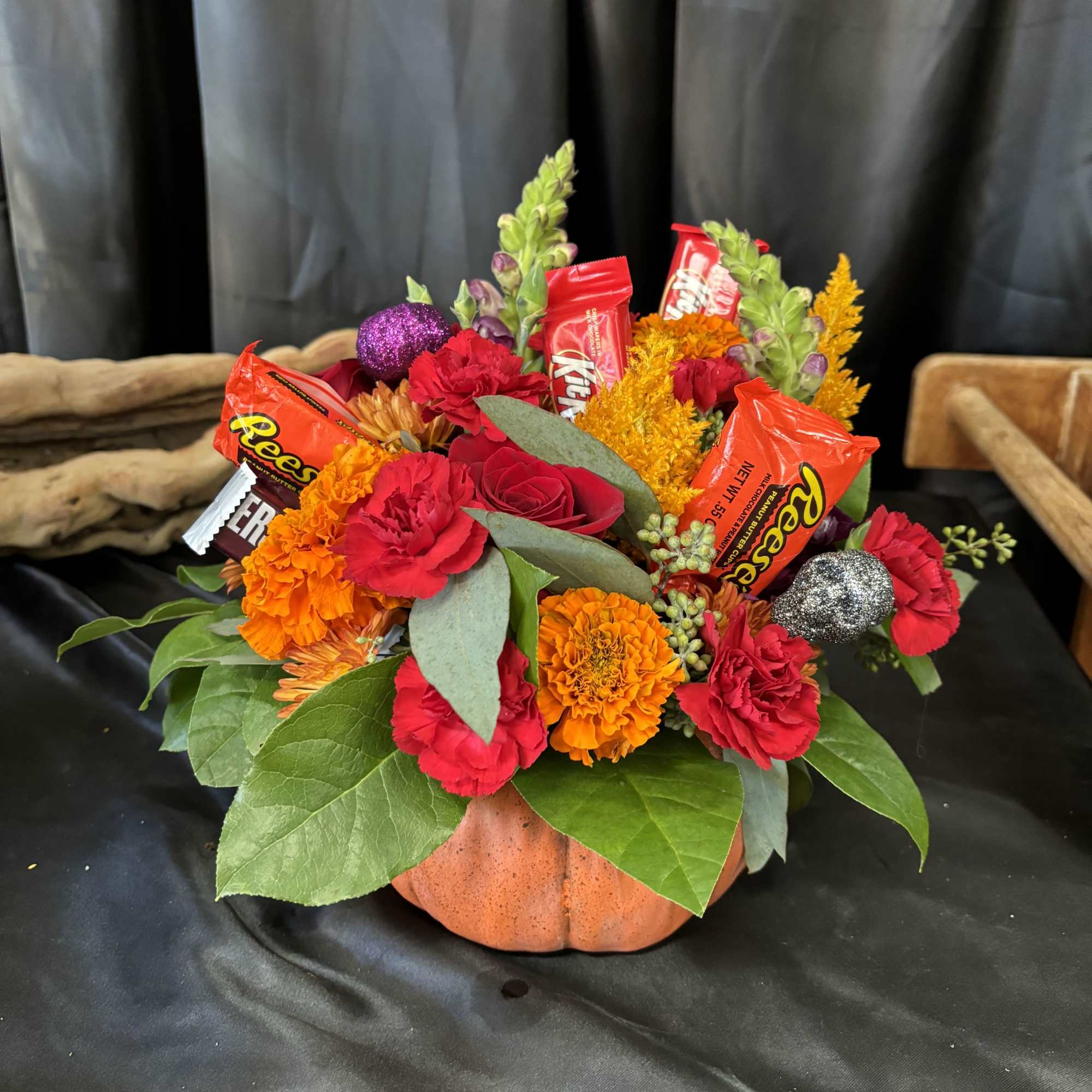Pumpkin-shaped floral arrangement with candy bars and bright flowers