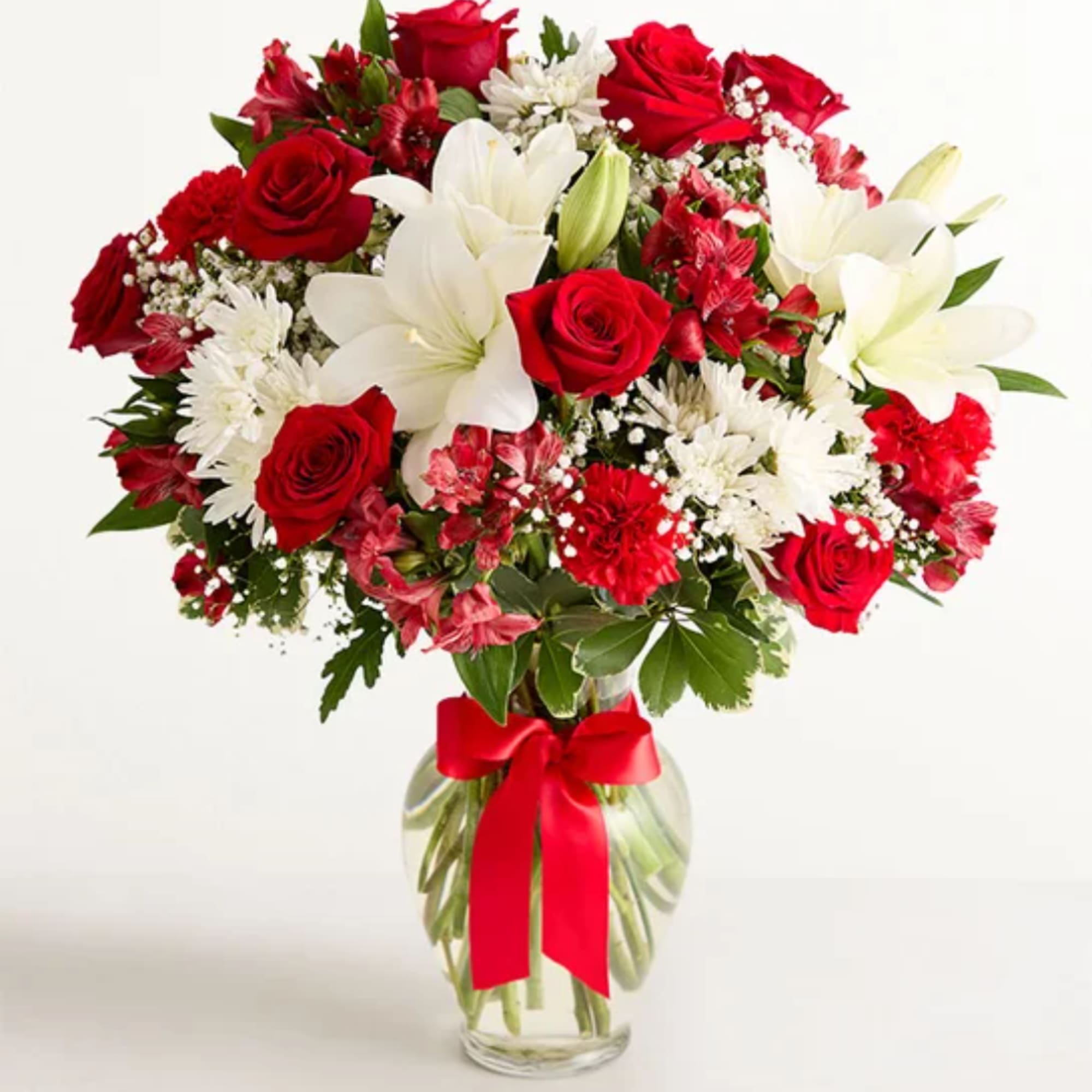 Red roses and white lilies in a glass vase with a red ribbon