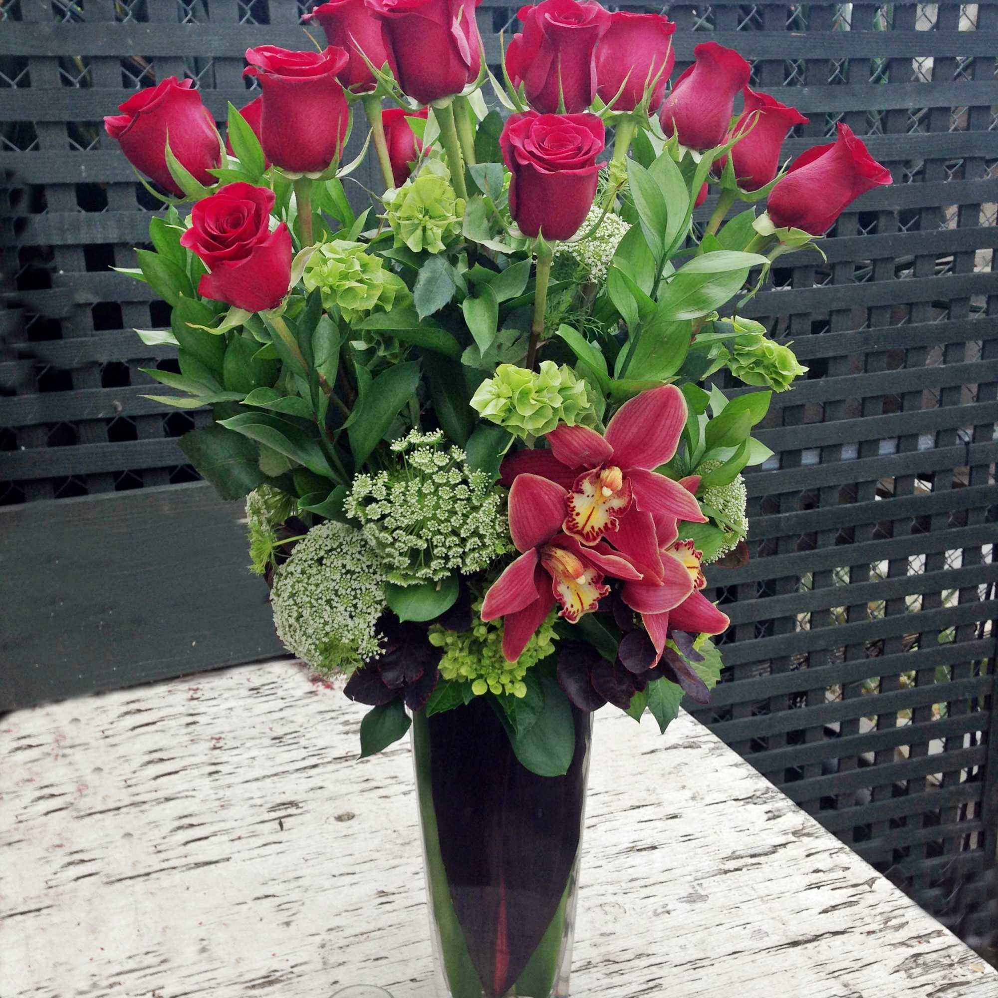 Red roses and pink orchids in a tall glass vase