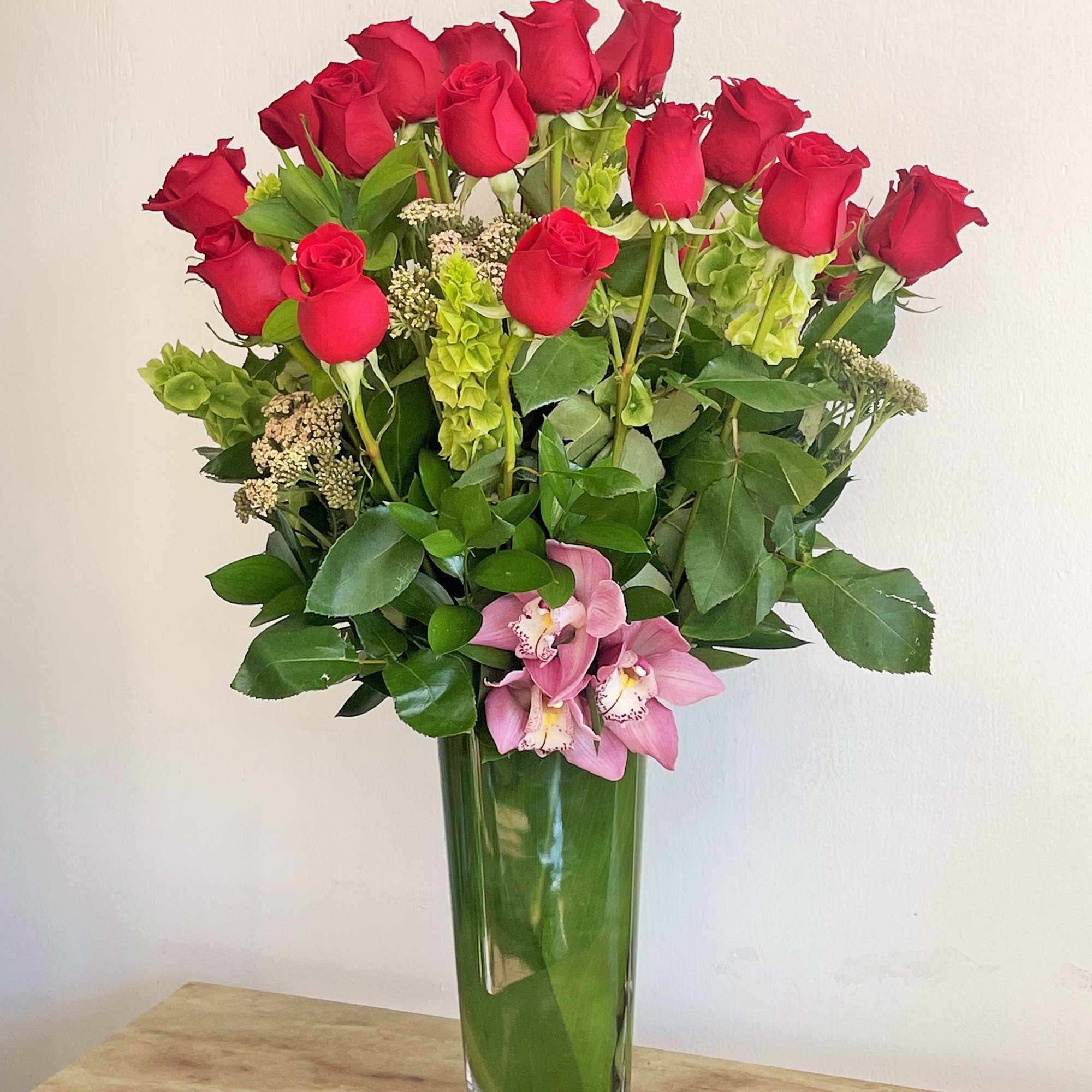 Red roses and pink orchids in a tall glass vase, photo 2 of 2