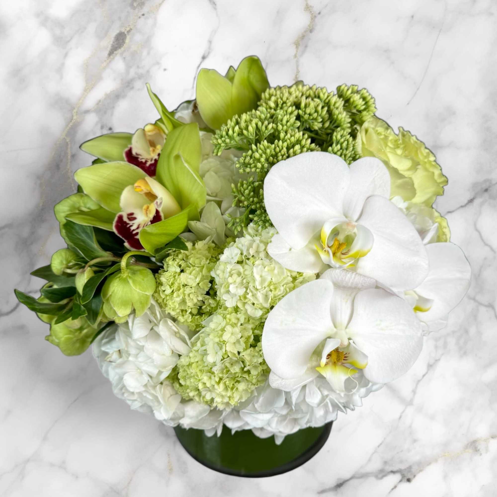 Green and white floral arrangement in a round vase