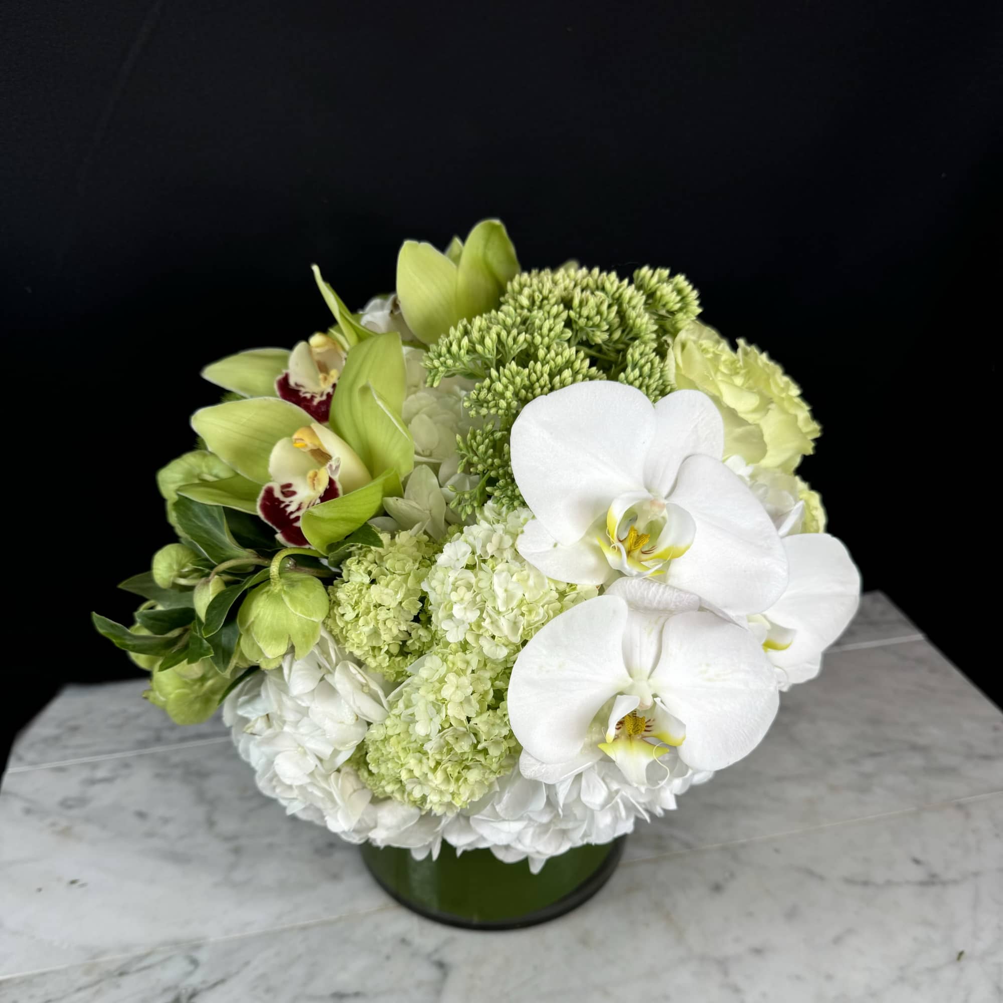 Green and white floral arrangement in a low round vase
