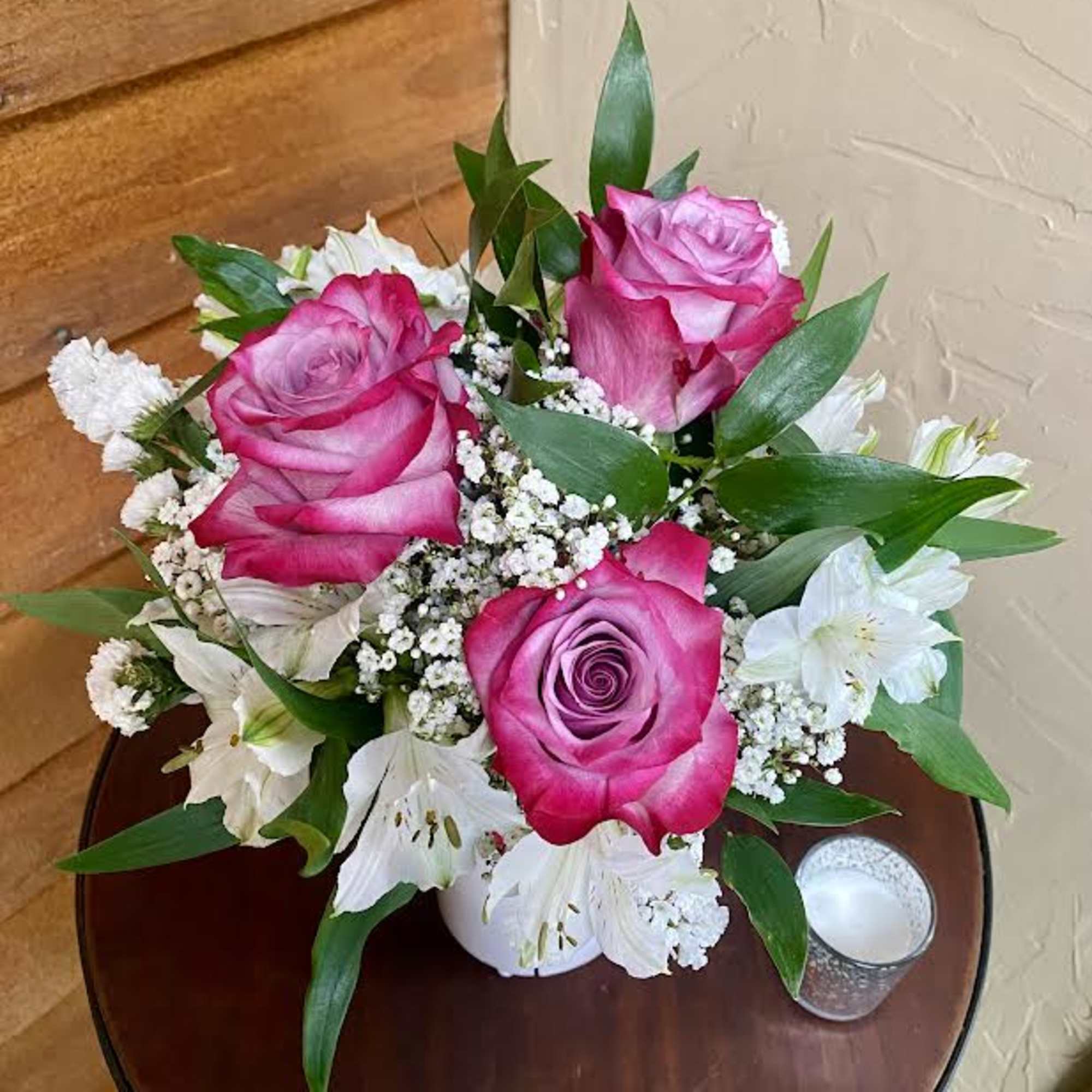 Pink roses and white lilies arranged in a small white vase
