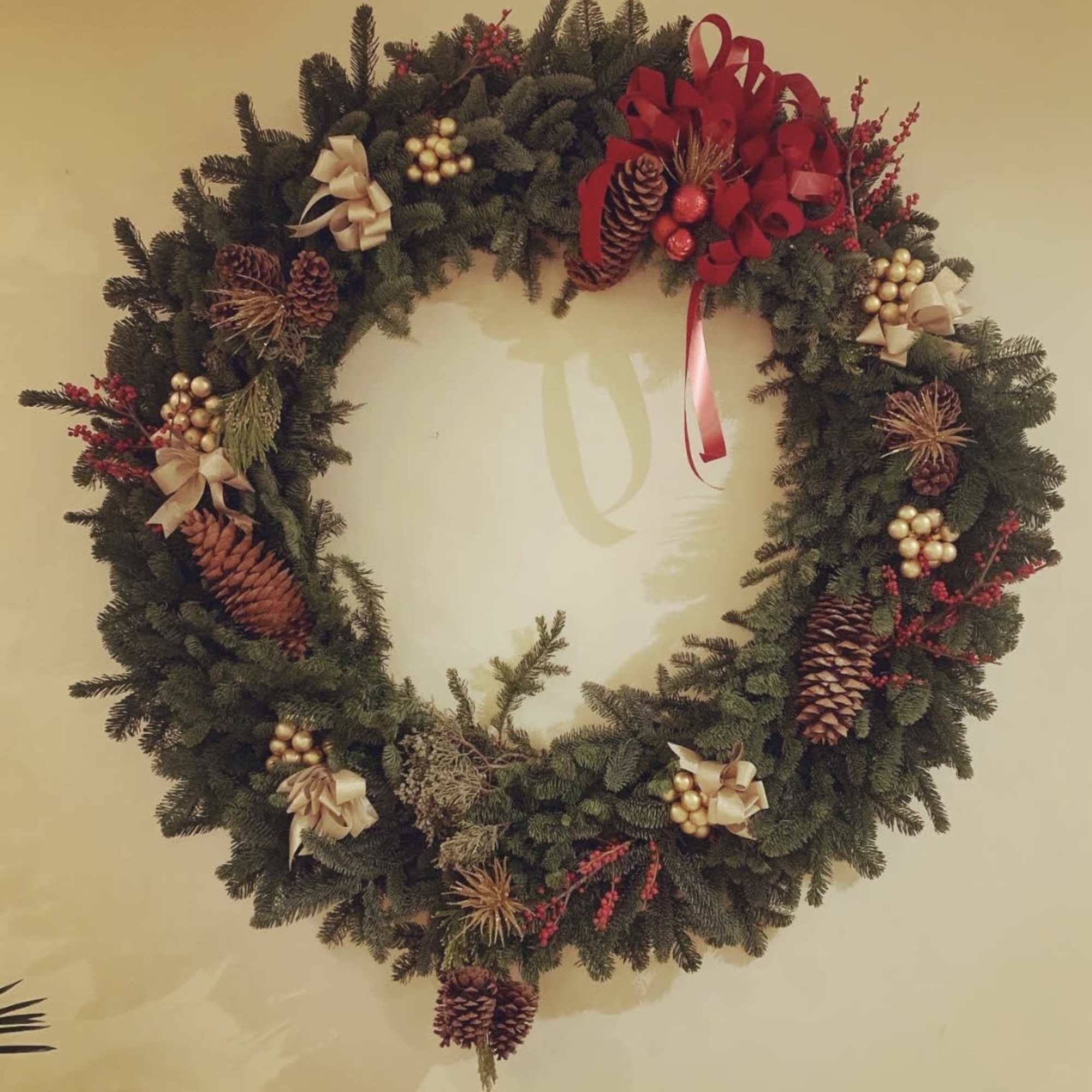 Christmas wreath with pinecones, red ribbon, and gold ornaments