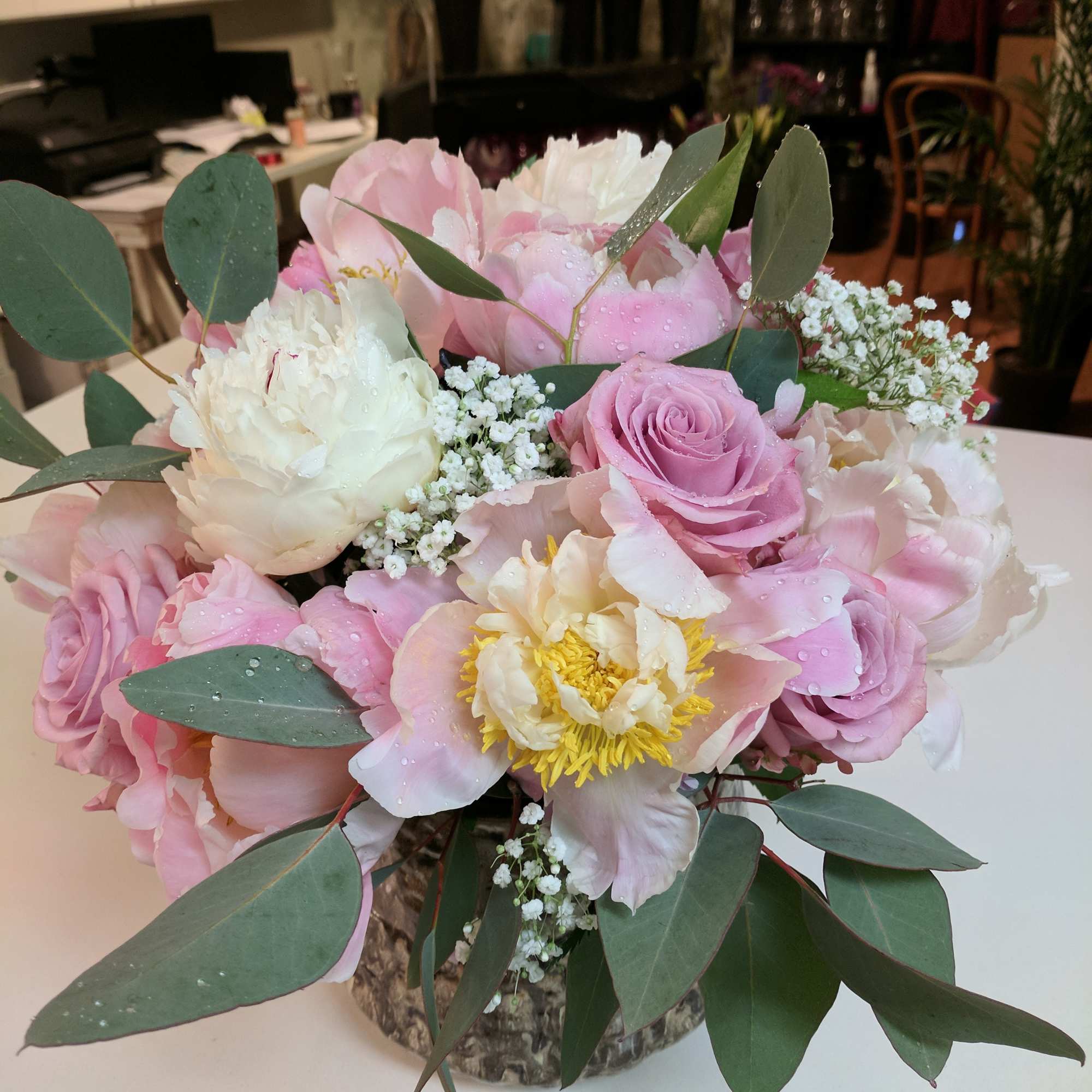 Pink and white bouquet of roses and peonies in a textured vase