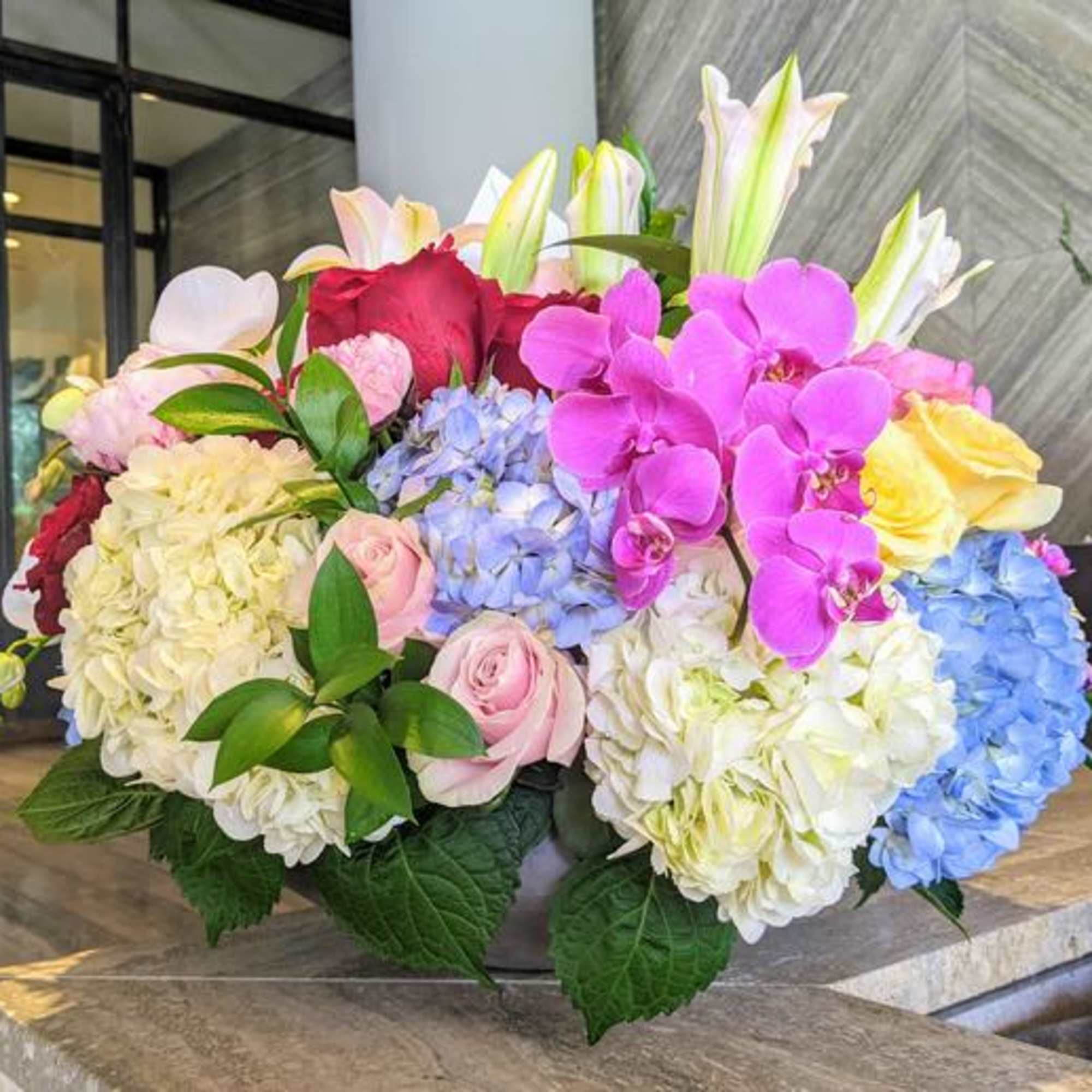 Large bouquet of hydrangeas, roses, lilies, and orchids in bright colors