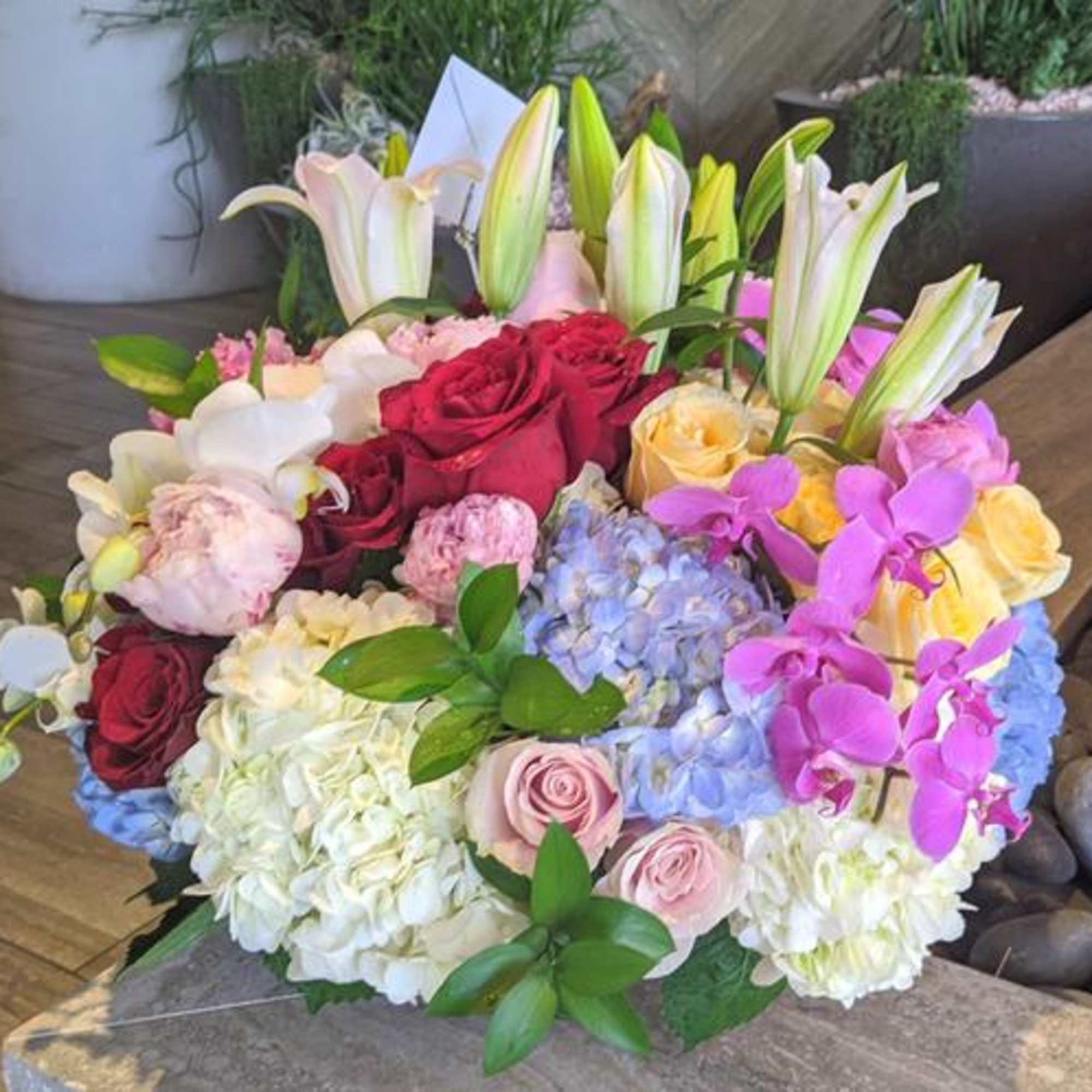 Bouquet of roses, hydrangeas, orchids, and lilies in pink, white, and blue