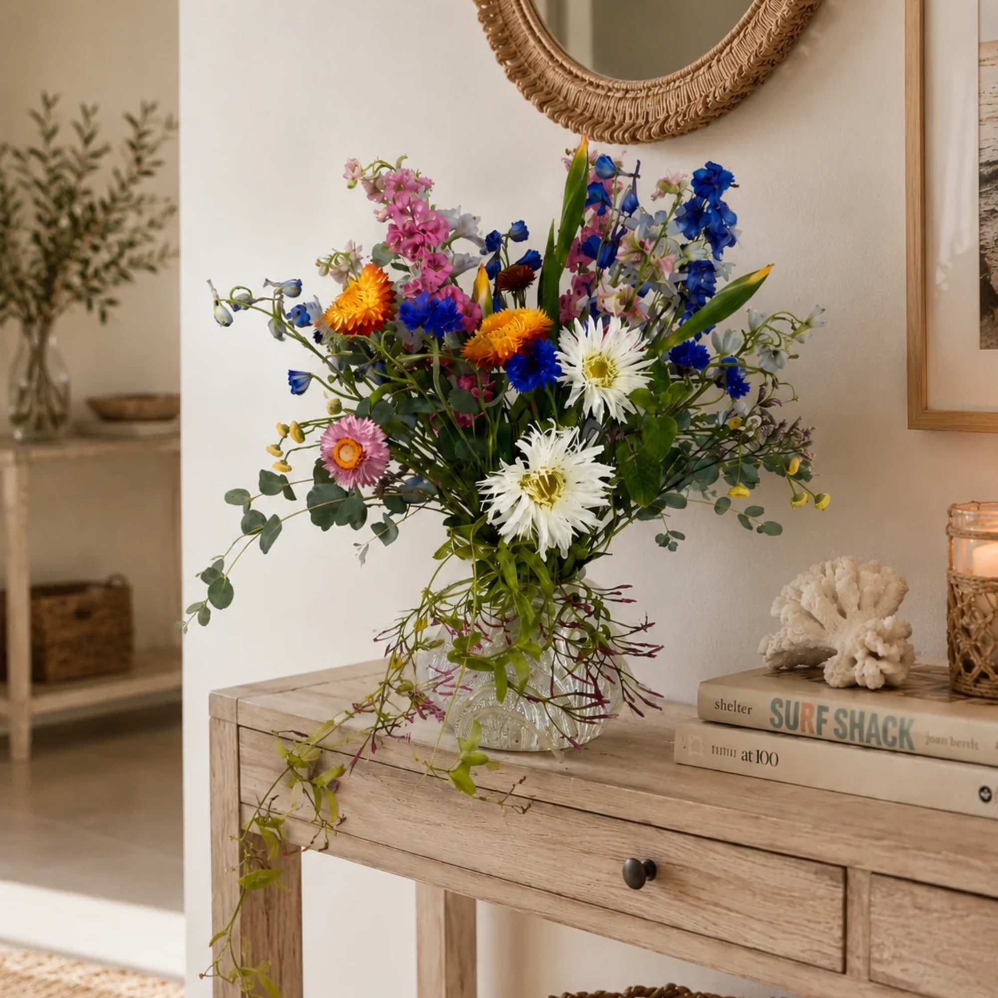 Mixed bouquet of colorful flowers in a clear glass vase on a wooden table