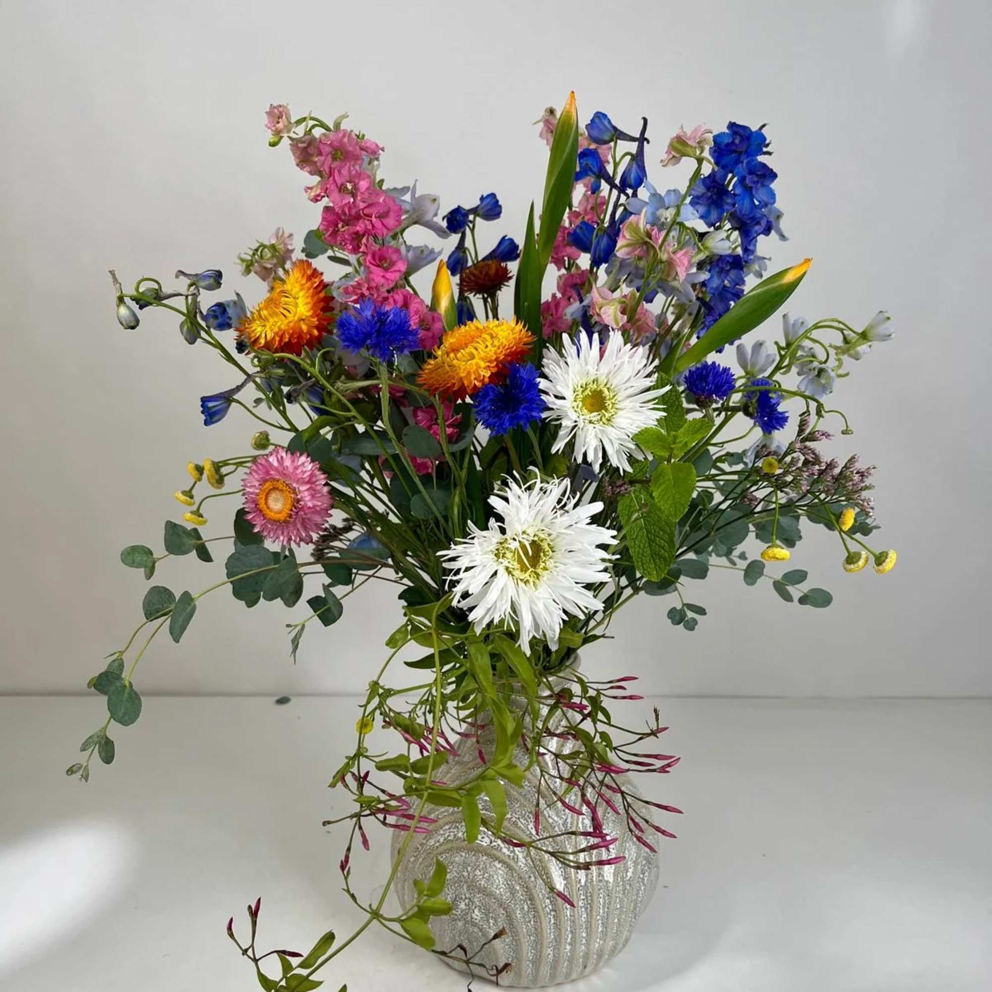 Mixed bouquet of colorful flowers in a silver vase