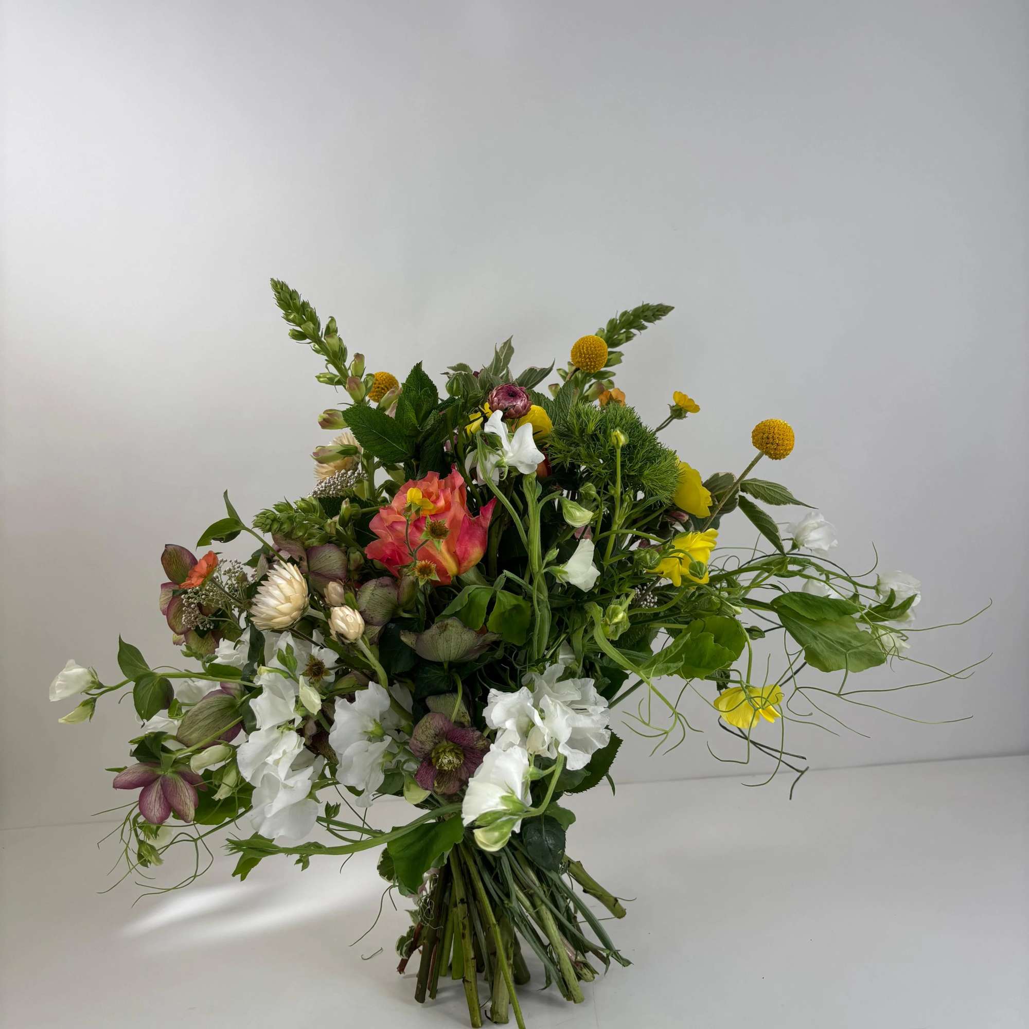 Loose bouquet of mixed white, yellow, pink, and green flowers
