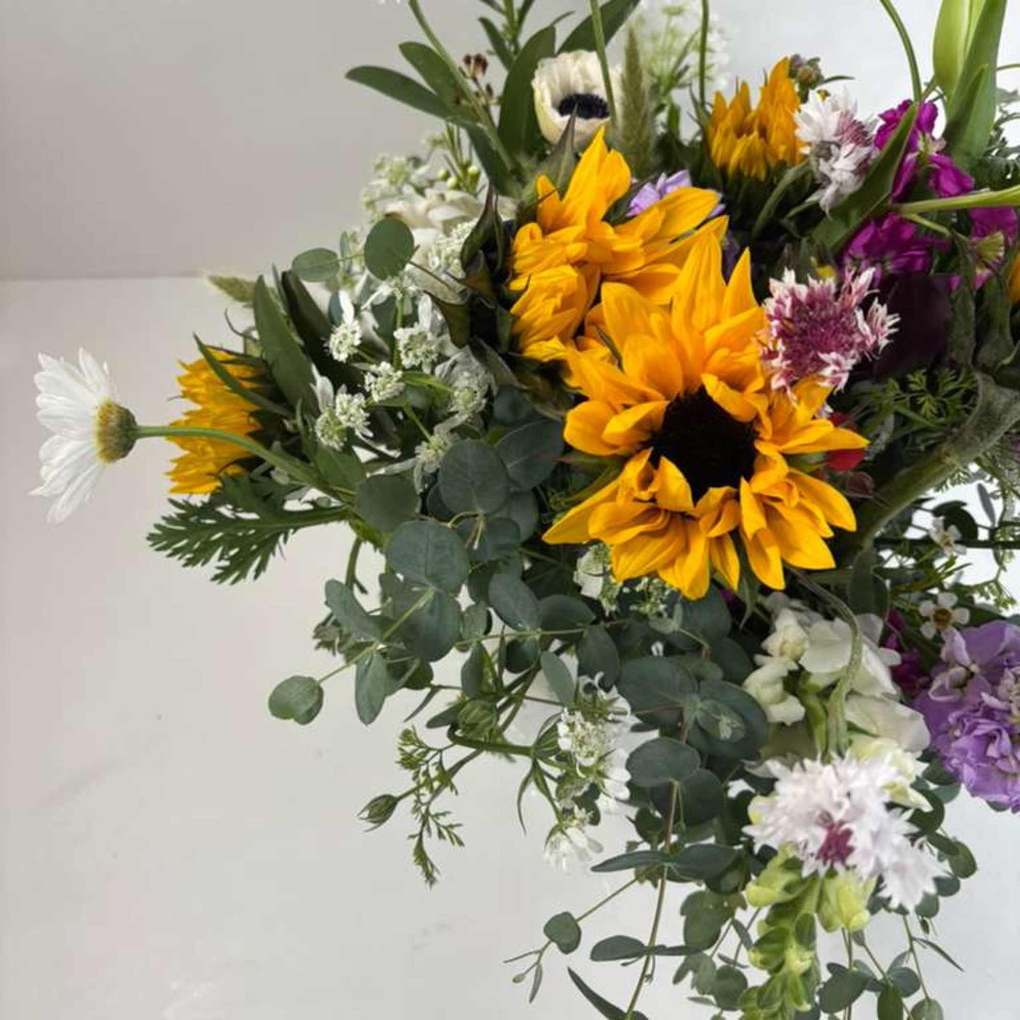 Mixed bouquet with sunflowers, white daisies, and purple blooms