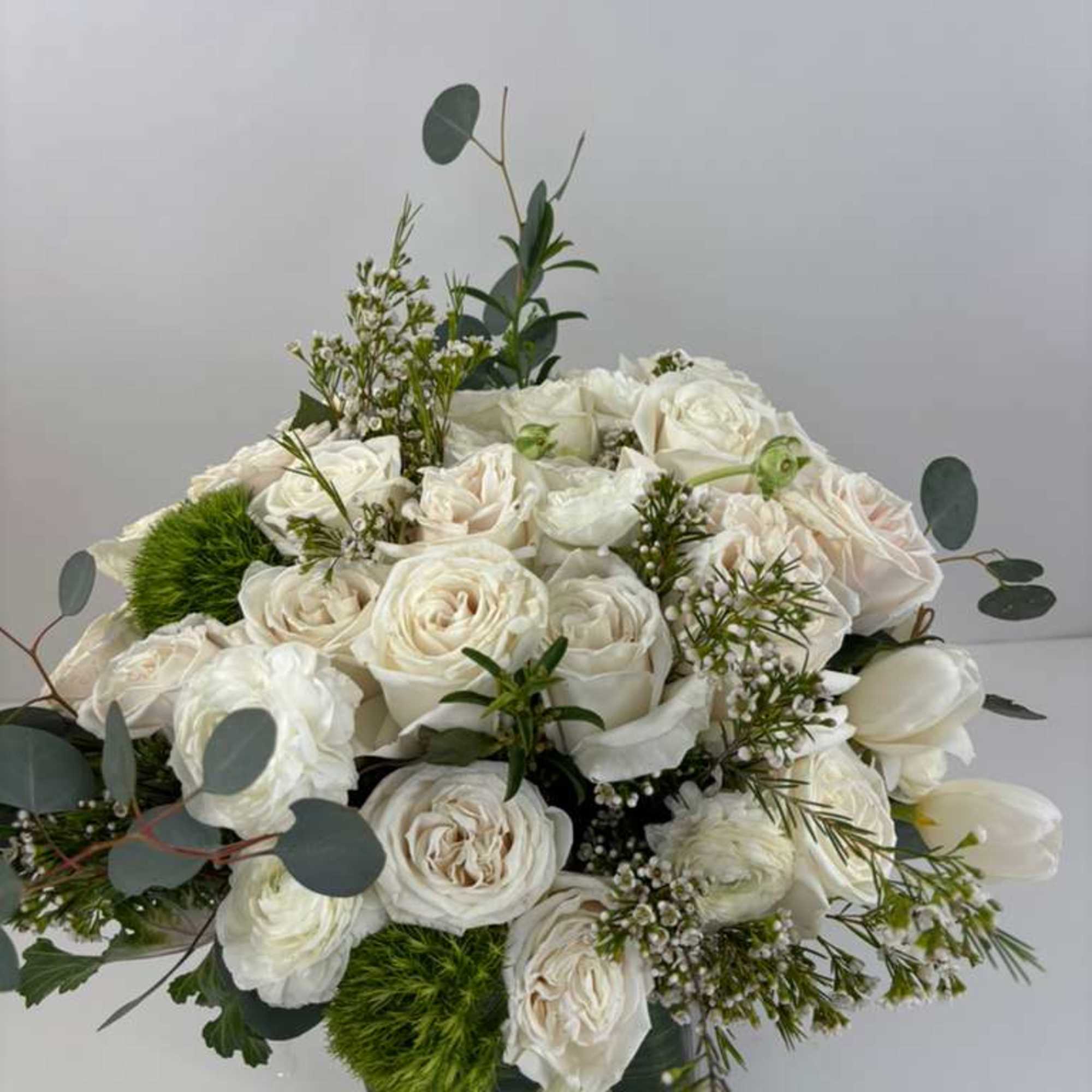 White rose bouquet with eucalyptus in a low black container
